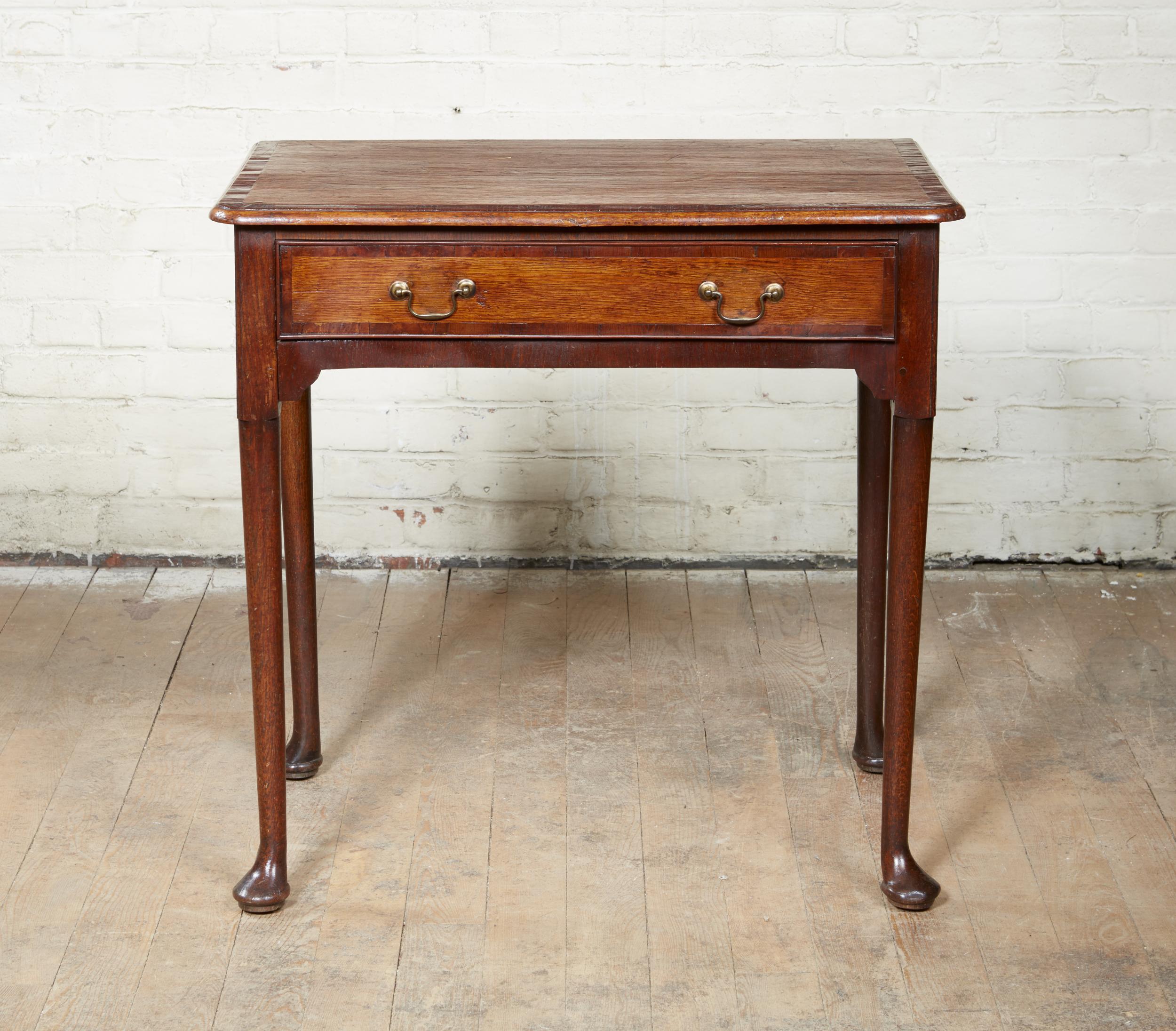 Good English early 18th century oak single drawer side table, the top with rounded corners, fruitwood cross banding and molded edge over single drawer similarly cross banded and retaining original swan neck pulls, over shaped apron and standing on