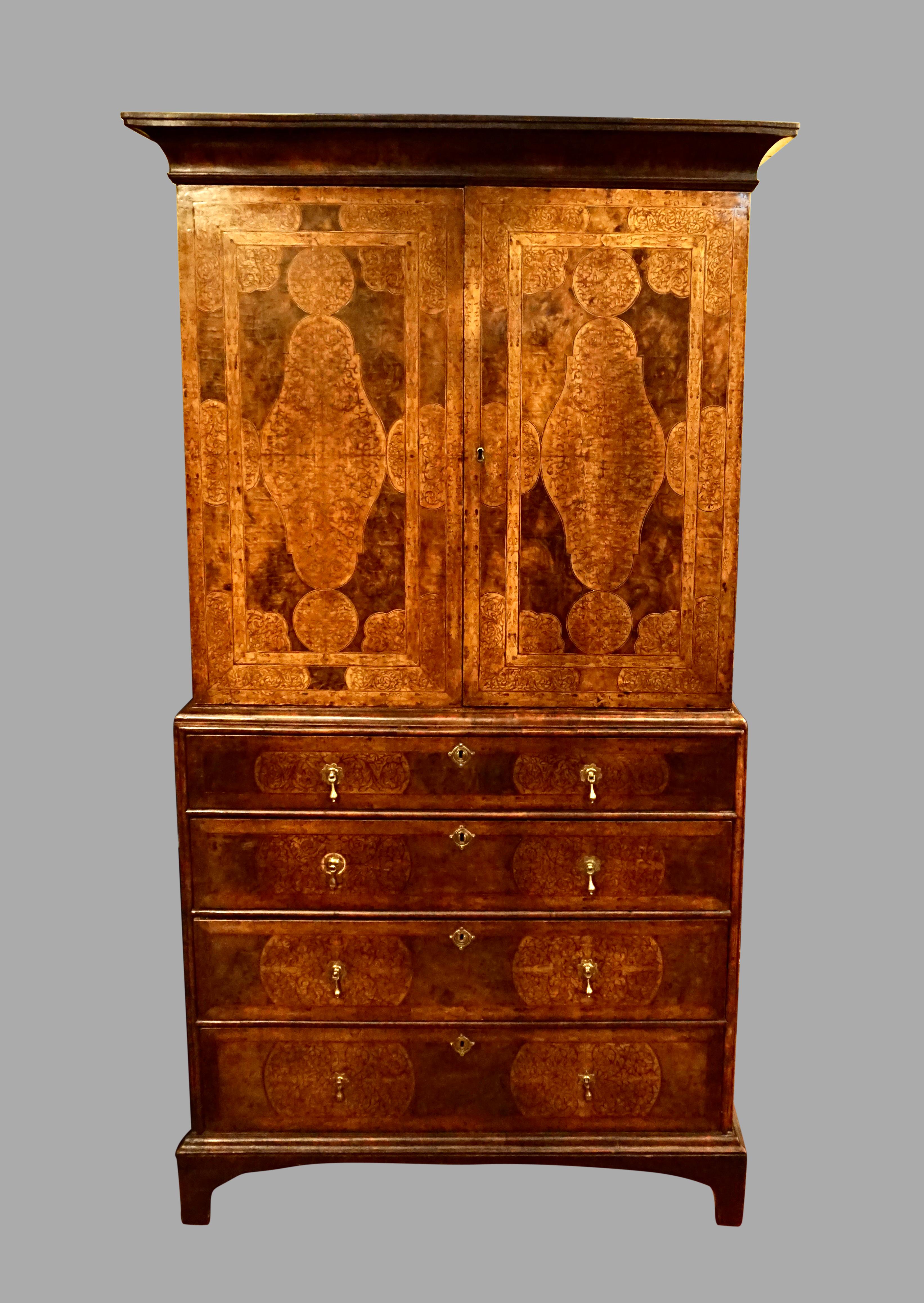 An elegant and rare Queen Anne period marquetry inlaid walnut cabinet-on-chest in two parts, the upper section with cabinet doors opening to reveal three adjustable shelves, the base, consisting of four graduated marquetry inlaid drawers supported