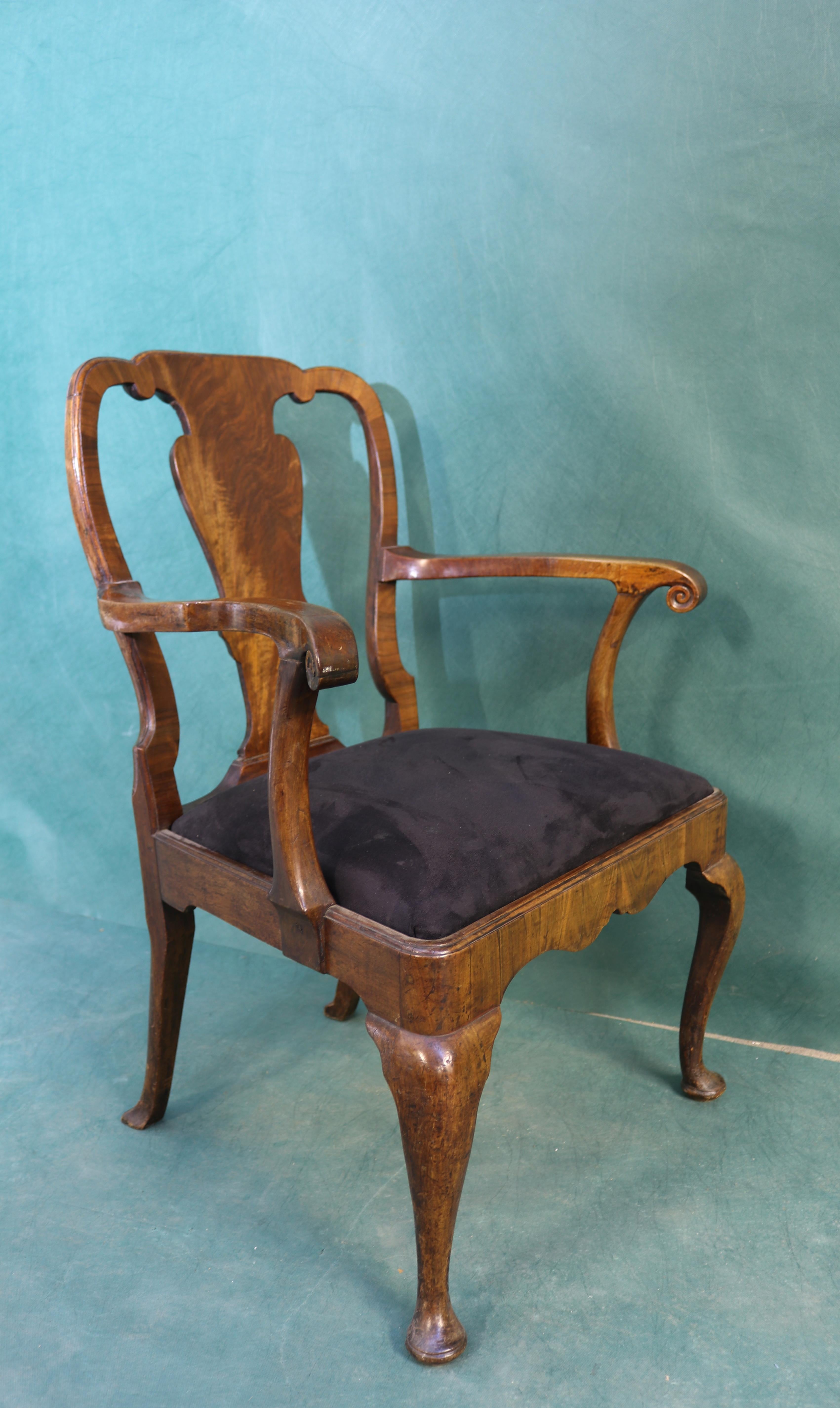 Handsome Queen Anne period walnut armchair, with fiddle-shaped back and crossbanded frame. Well shaped arms terminating in a scroll. The drop in seat housed within a cross-banded apron raised upon cabriole legs.

Measurements:
95cms high
69cms -