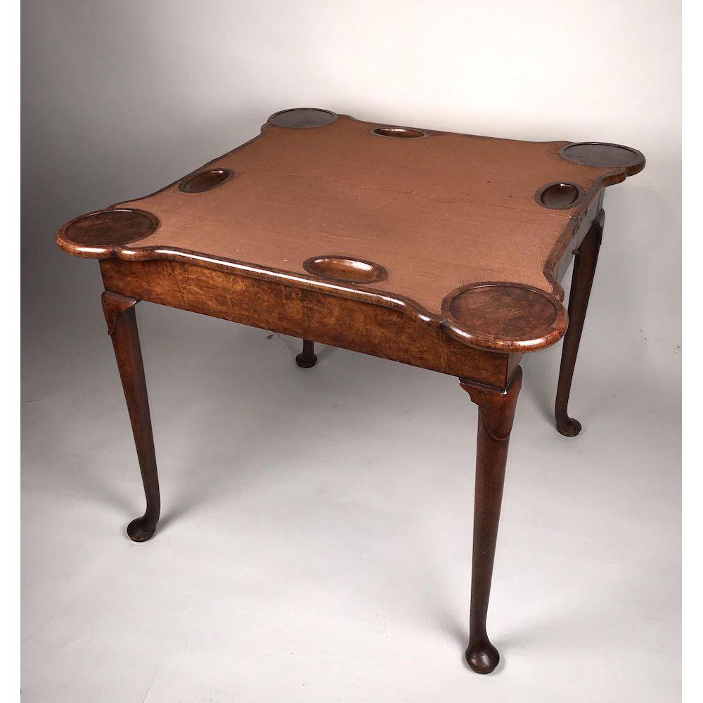 Ein geschnitzter Nussbaumspieltisch aus dem frühen 18. Jahrhundert aus der Queen-Anne-Zeit.
Um 1710.

Furniert in wohlgeformtem Nussbaum mit Fischgrät-Federbändern.
Der kühne, klappbare Aufsatz ist so geformt, dass Kerzenständer und Perlenketten zum