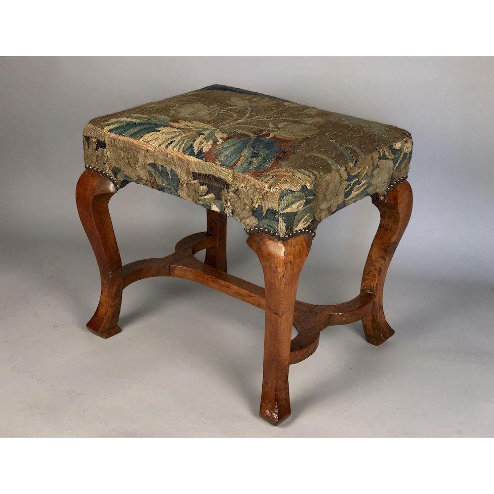 A Queen Anne period walnut stool.
Early 18th century, circa 1710.

Upholstered in 17th century tapestry, and close-nailed.
Original stretchers and rails, all firm in the joints. Ready to use, in excellent condition.

Ref: 
In 'The Shorter Dictionary