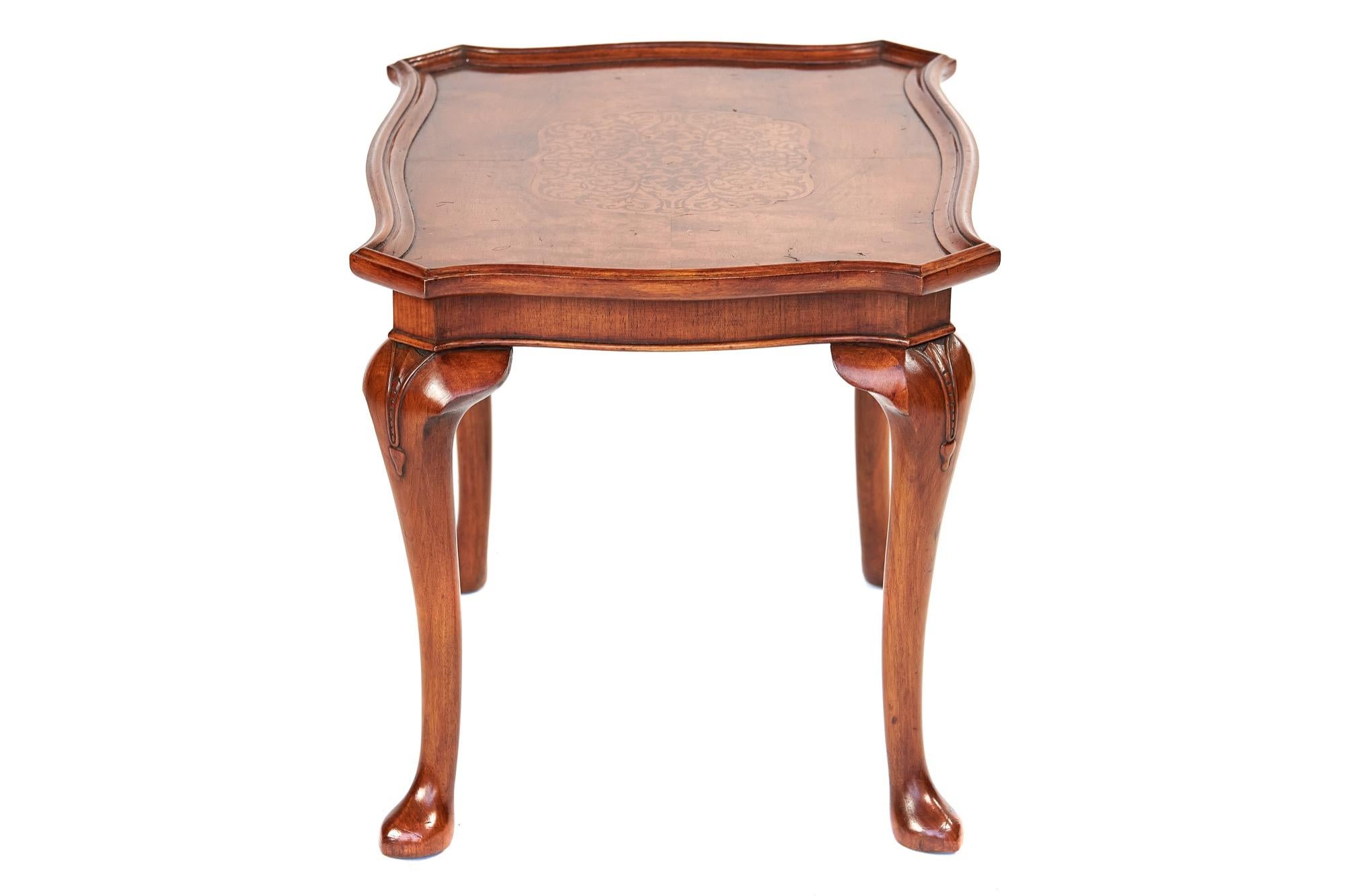 Table basse en noyer de style Queen Anne, vers 1920
Dessus en forme avec moulure sur le pourtour, 
Décoration centrale incrustée de motifs d'algues, 
tablier en noyer façonné, 
reposant sur 4 pieds cabrioles en noyer,
Sculpture sur les genoux et le
