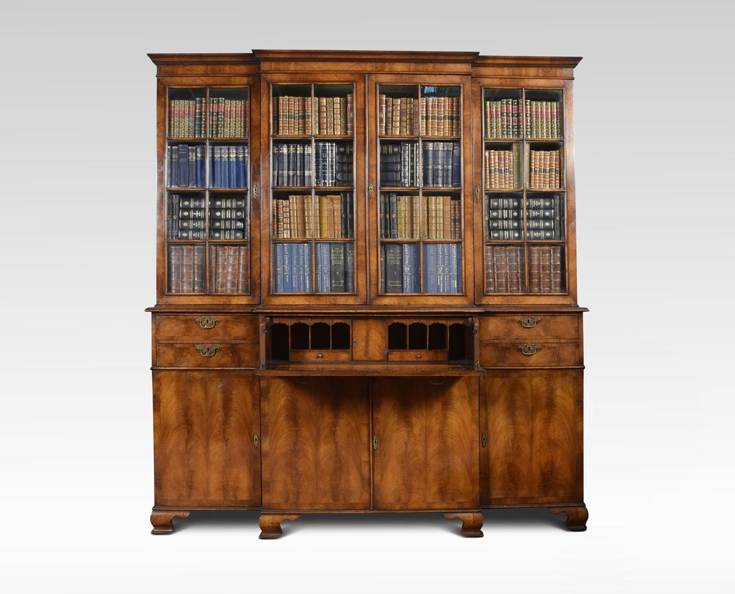 Queen Anne revival walnut four door bookcase, the projecting cornice above, four large glazed doors opening to reveal fixed shelved interior. To the base section fitted with a central secretaire drawer and original inset leather. Flanked by short