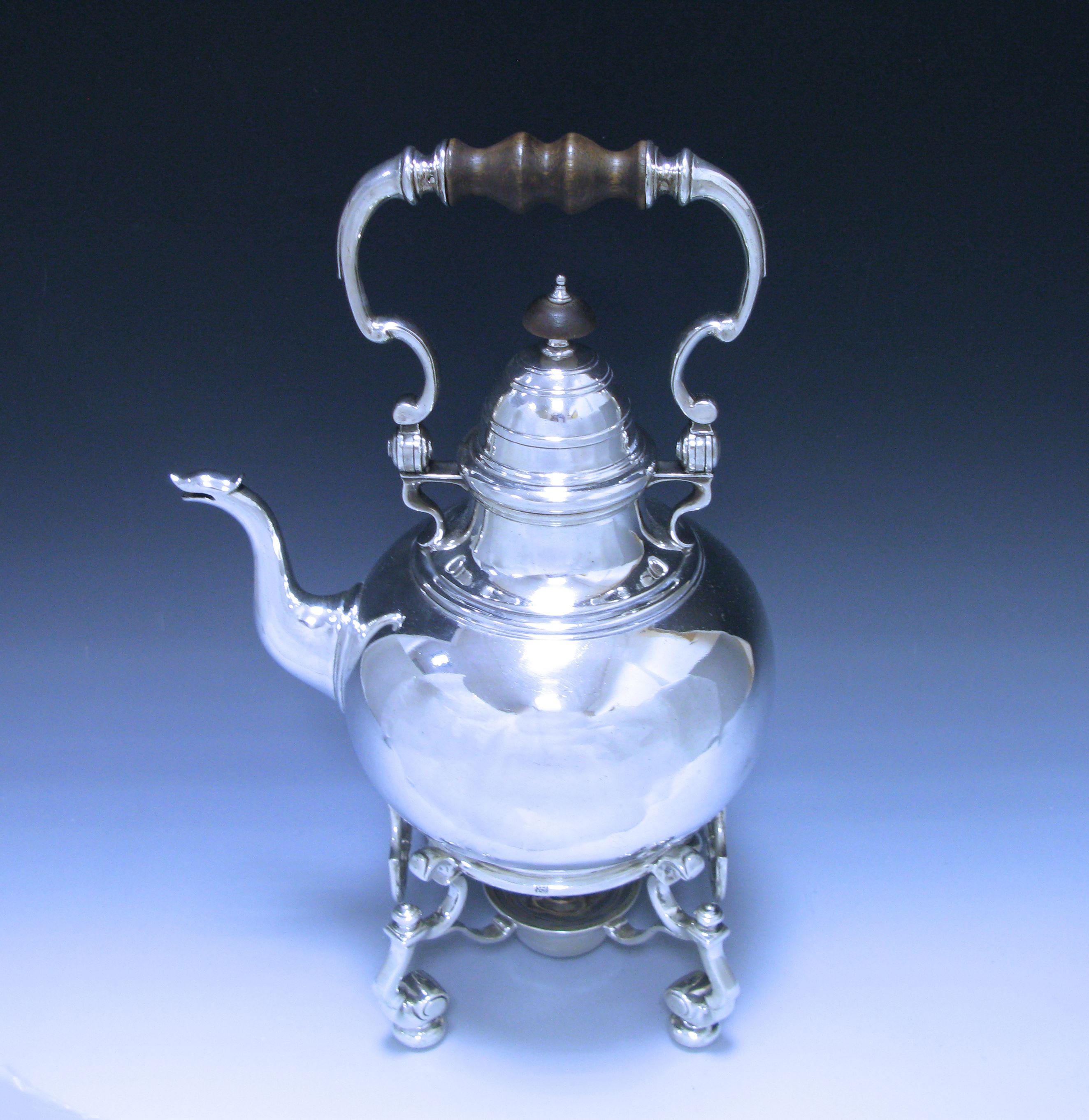 This antique Queen Anne sterling silver tea kettle on stand is of circular rounded form onto a collet foot. The kettle has the original hinged hallmarked lid which is domed and has a wooden finial. The kettle is fitted with an impressive sterling