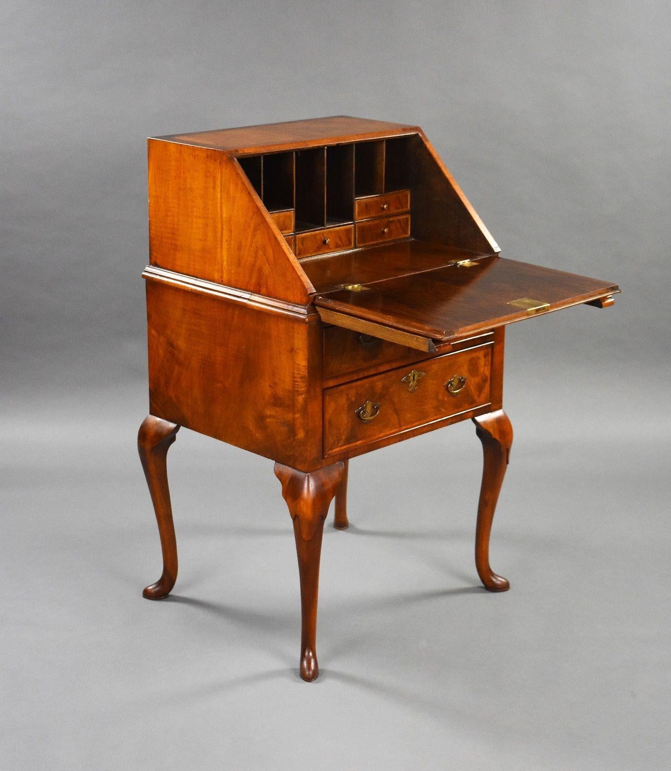 Queen Anne Style 1930s walnut bureau in good condition. The fall sits on two pull out slides with a fitted interior with drawers and pigeon holes. The bureau stands on elegant cabriol legs.