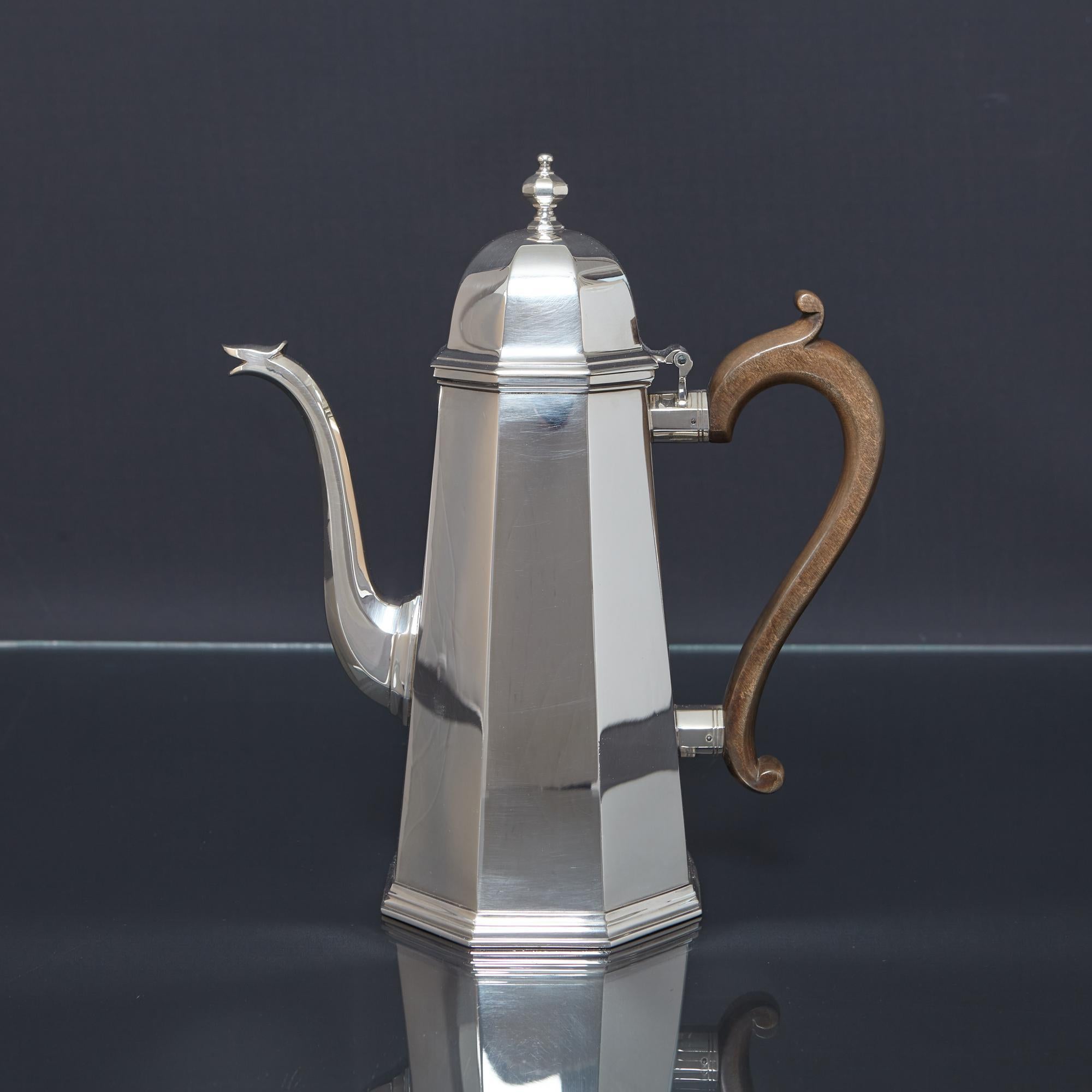 A superb quality, silver coffee pot in the Queen Anne style, determined by its octagonal body and panelled swan neck silver spout. The octagonal hinged lid is surmounted by a panelled finial and there is an applied stepped decoration about the base,