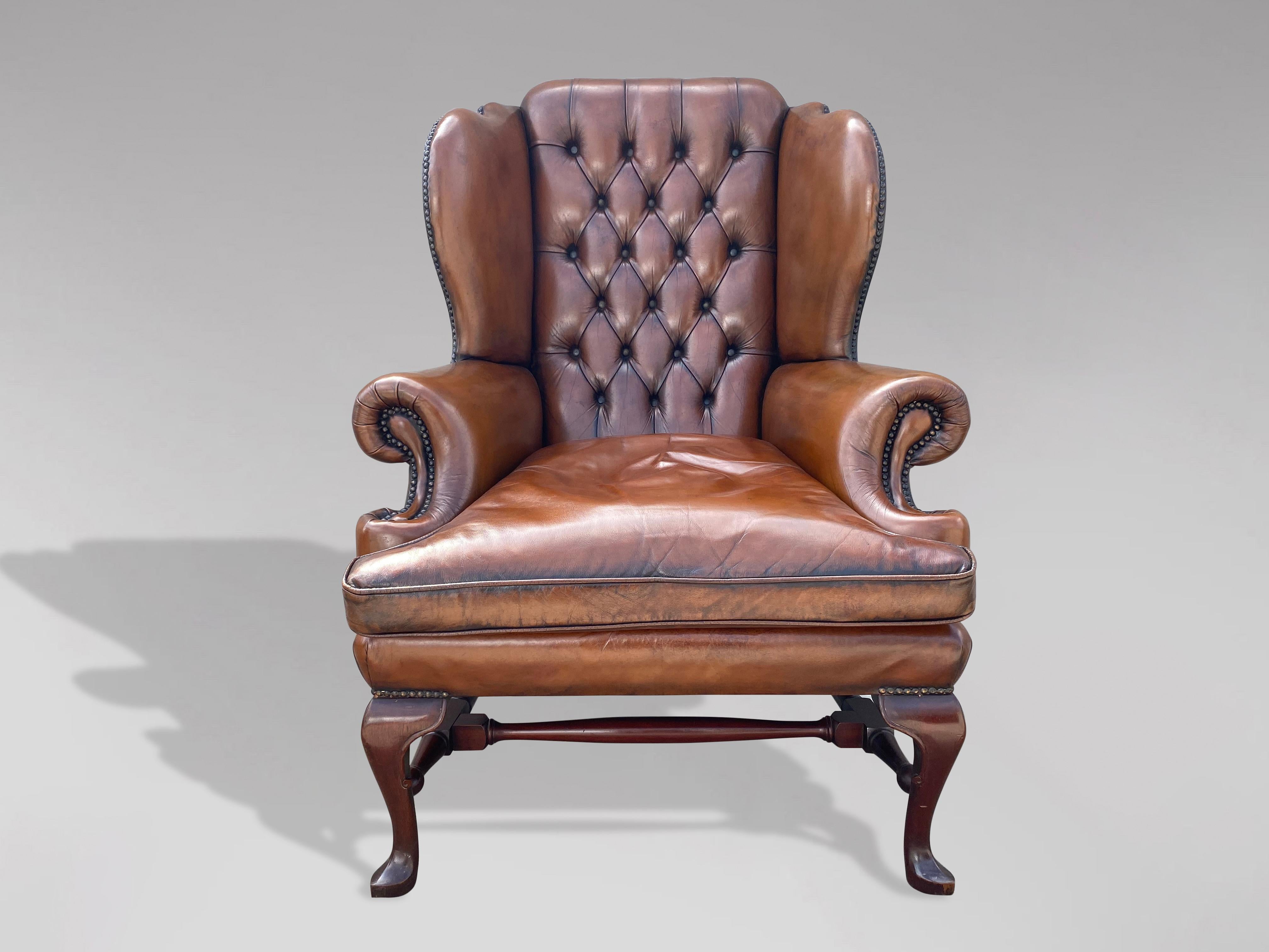 A great quality 20th century brown leather Queen Anne style wing armchair with buttoned back and loose feathered cushion, standing on mahogany front cabriole feet united by shaped stretchers. Great colour. Very comfortable seating.

The dimensions