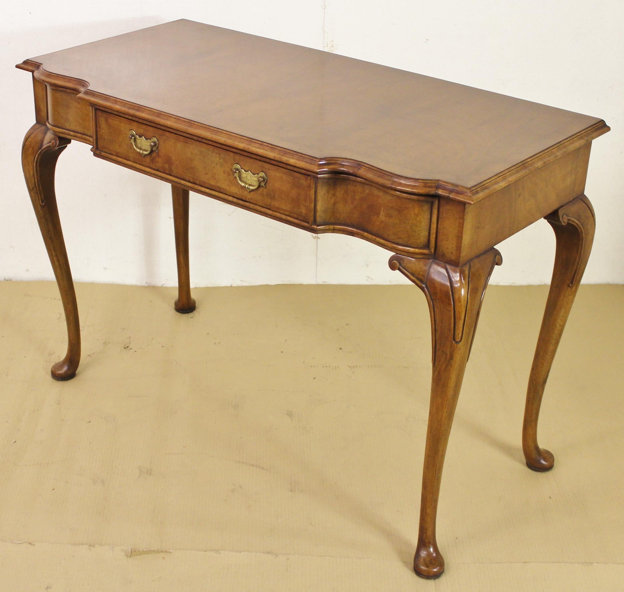 An excellent burr walnut console table in the Queen Anne style and of generous proportions. Very well constructed in solid walnut with attractive burr walnut veneers. The serpentine shaped top is cross banded and is surrounded with thumb-nail