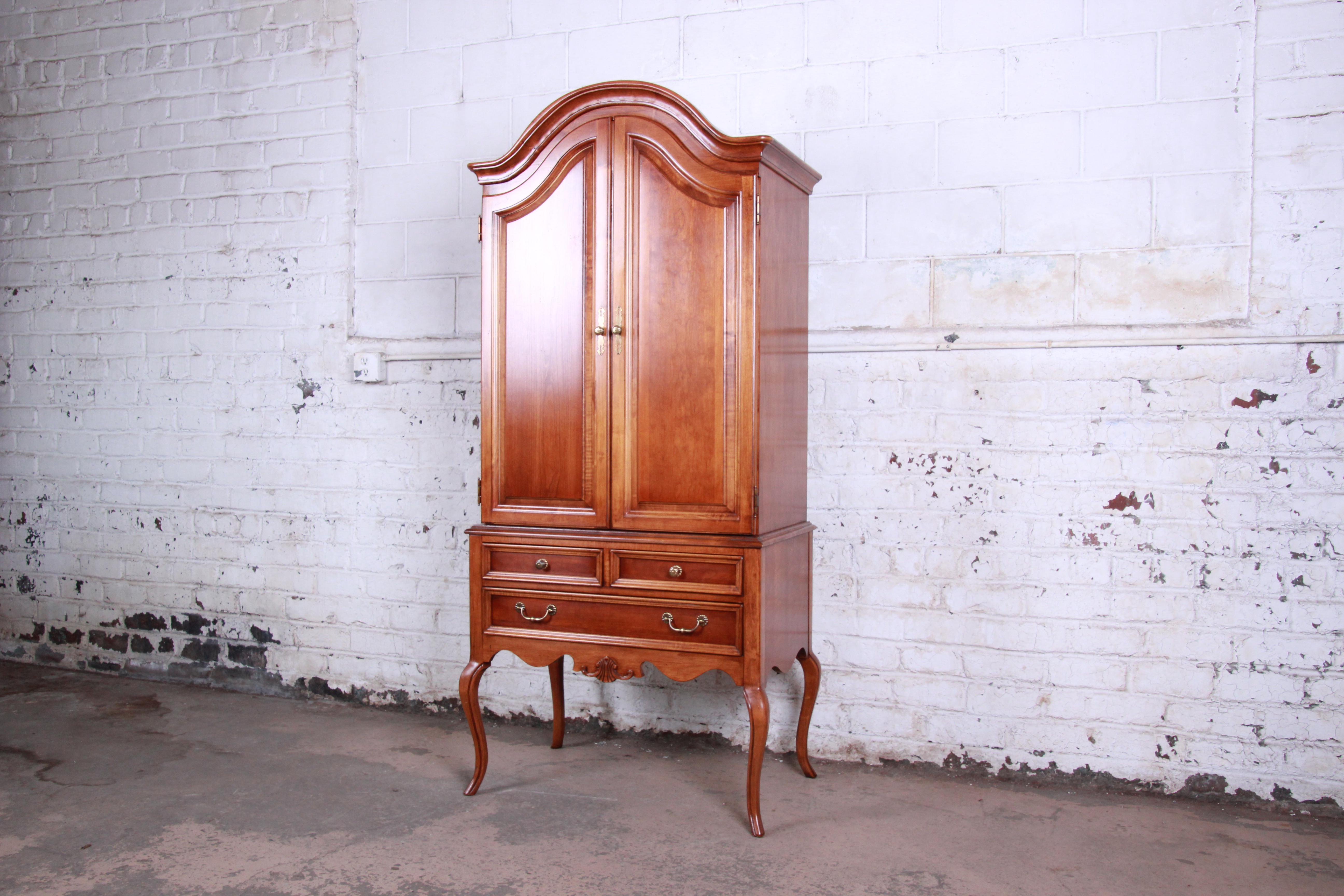 A beautiful Queen Anne style cherrywood armoire dresser by Lexington Furniture. The dresser features gorgeous cherrywood grain, nice carved details, and tall cabriole legs. It offers ample storage, with four deep dovetailed drawers behind two doors