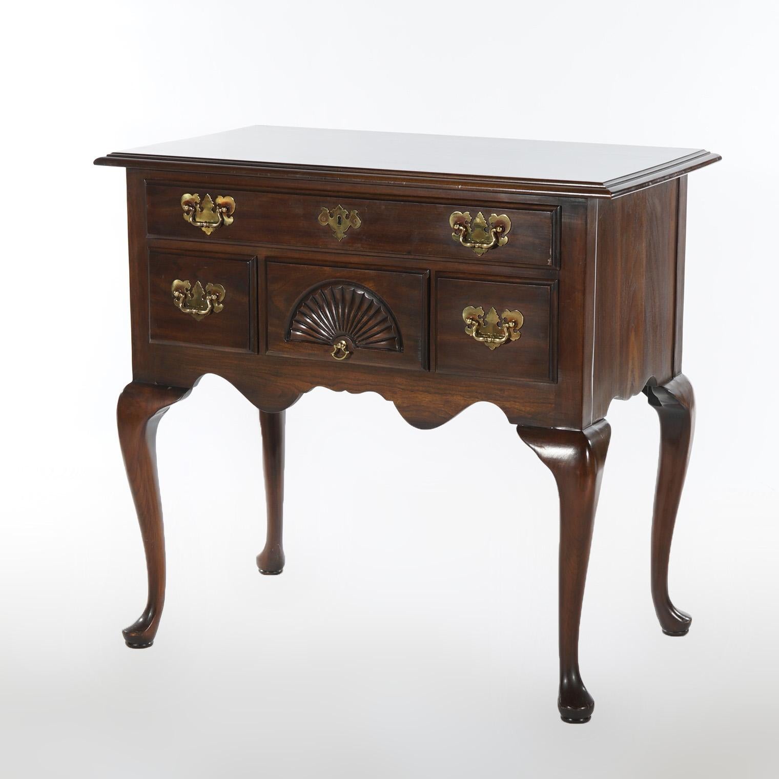 A Queen Anne style lowboy by Harden offers cherry construction with case having single long drawer over three smaller drawers (the center with a carved stylized fan), and shaped apron; raised on cabriole legs terminating in pad feet; cast brass