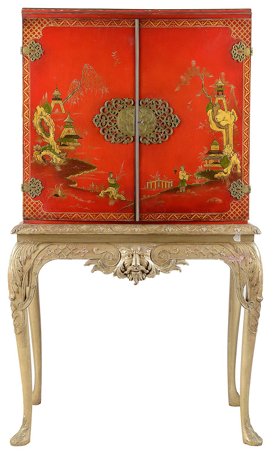 A good quality 1920s Queen Anne style red lacquer, cabinet on stand, having chinoiserie decoration to the doors and sides, depicting pagoda buildings and mountains in the distance, people wondering amongst the gardens, brass fretwork escutcheons and