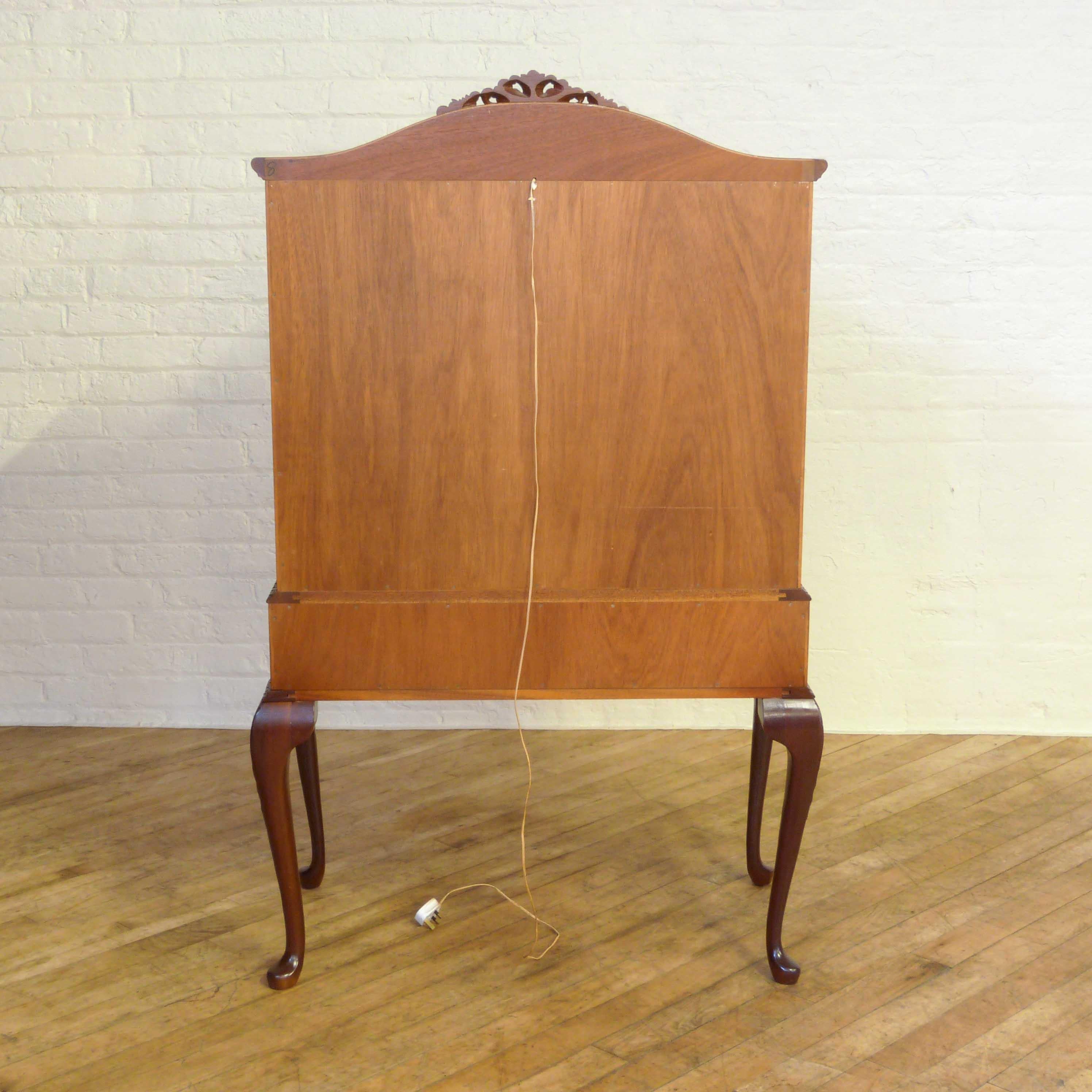 A Queen Anne style mahogany cocktail cabinet with a well shaped dome top with a carved pediment. The central section is nicely fitted with two shelves and a brushing slide to serve and mix from. The base has two drawers and is also well carved to