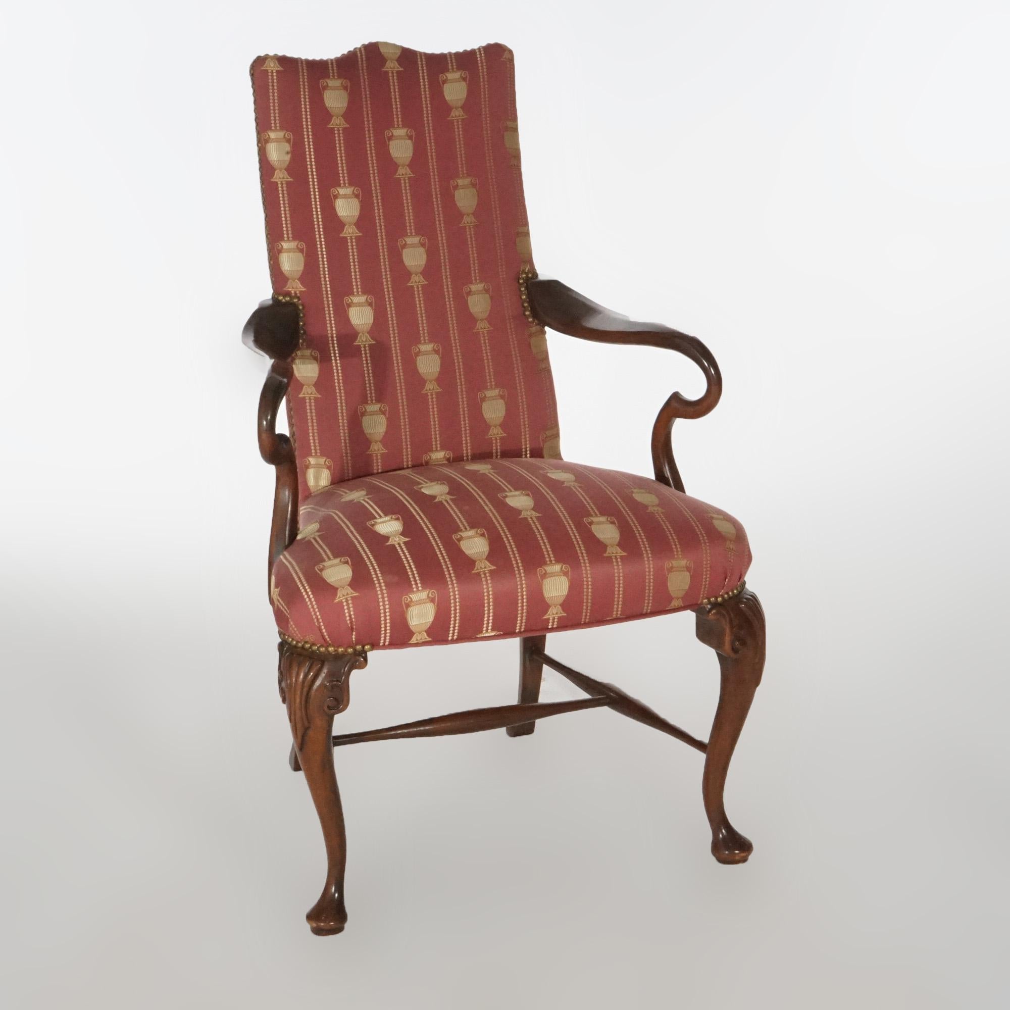 A Queen Anne style armchair offers upholstered back and seat over mahogany base having carved foliate elements and raised on cabriole legs terminating in pad feet, circa 1940.

Measures- 41.25''H x 25.5''W x 26''D.