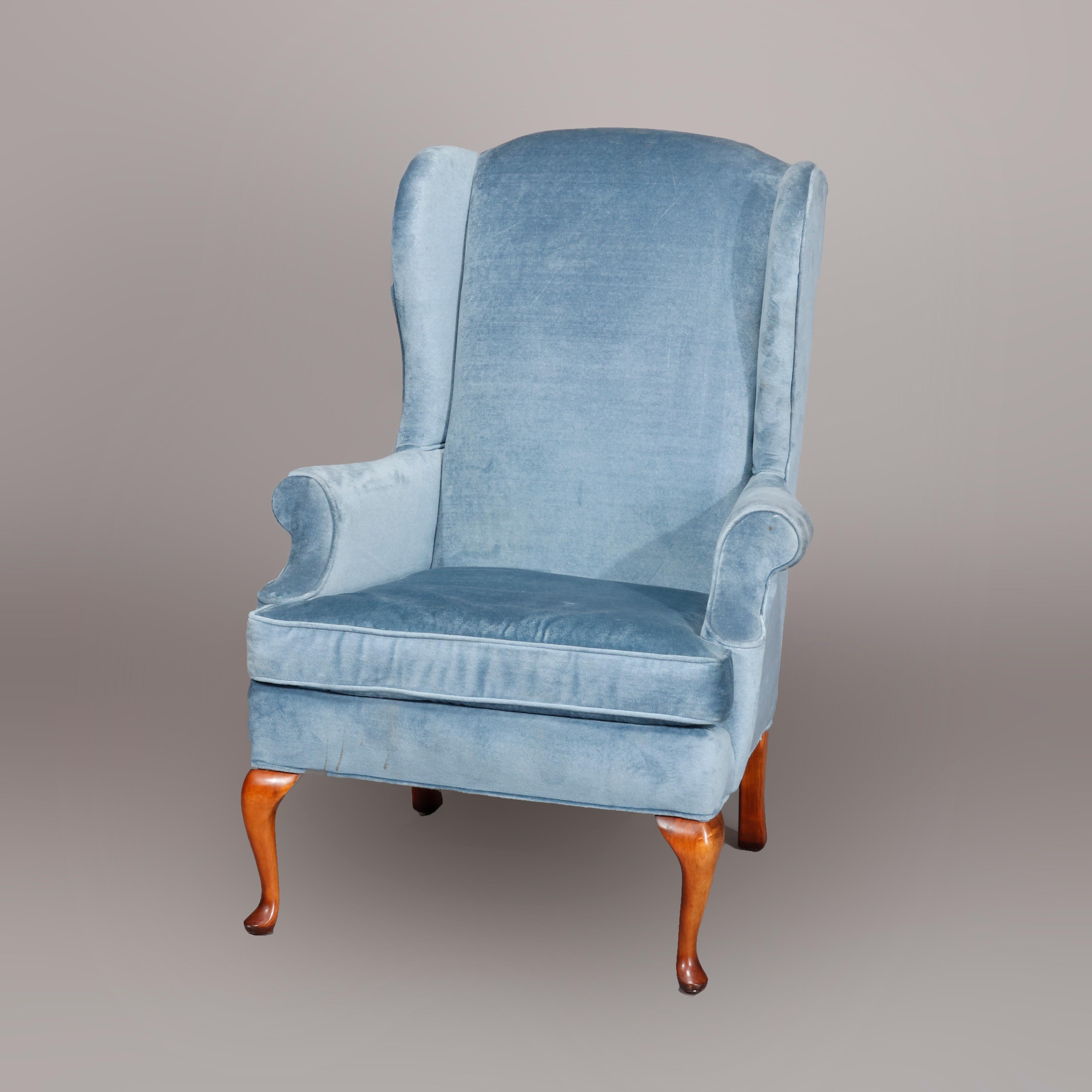 A Queen Anne style wingback chair offers blue upholstered chair by Laine Furniture with scroll arms, raised on cabriole mahogany legs, label as photographed, 20th century.

Measures: 45.5
