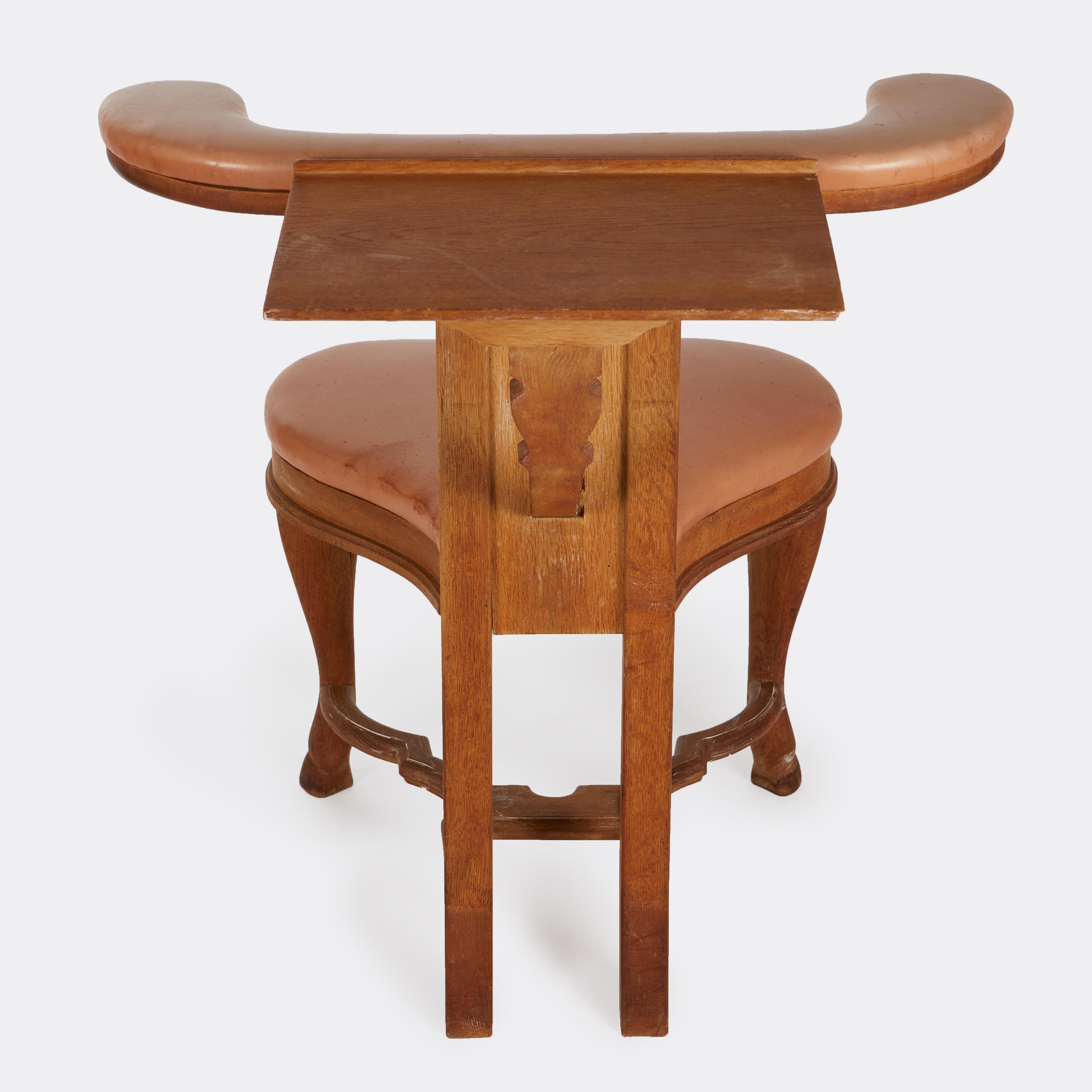 An antique hardwood reading chair with foldout surface on the back. This type of chair was used for both conventional seating, or if straddled, the small surface on the back serves as a reading or writing desk.