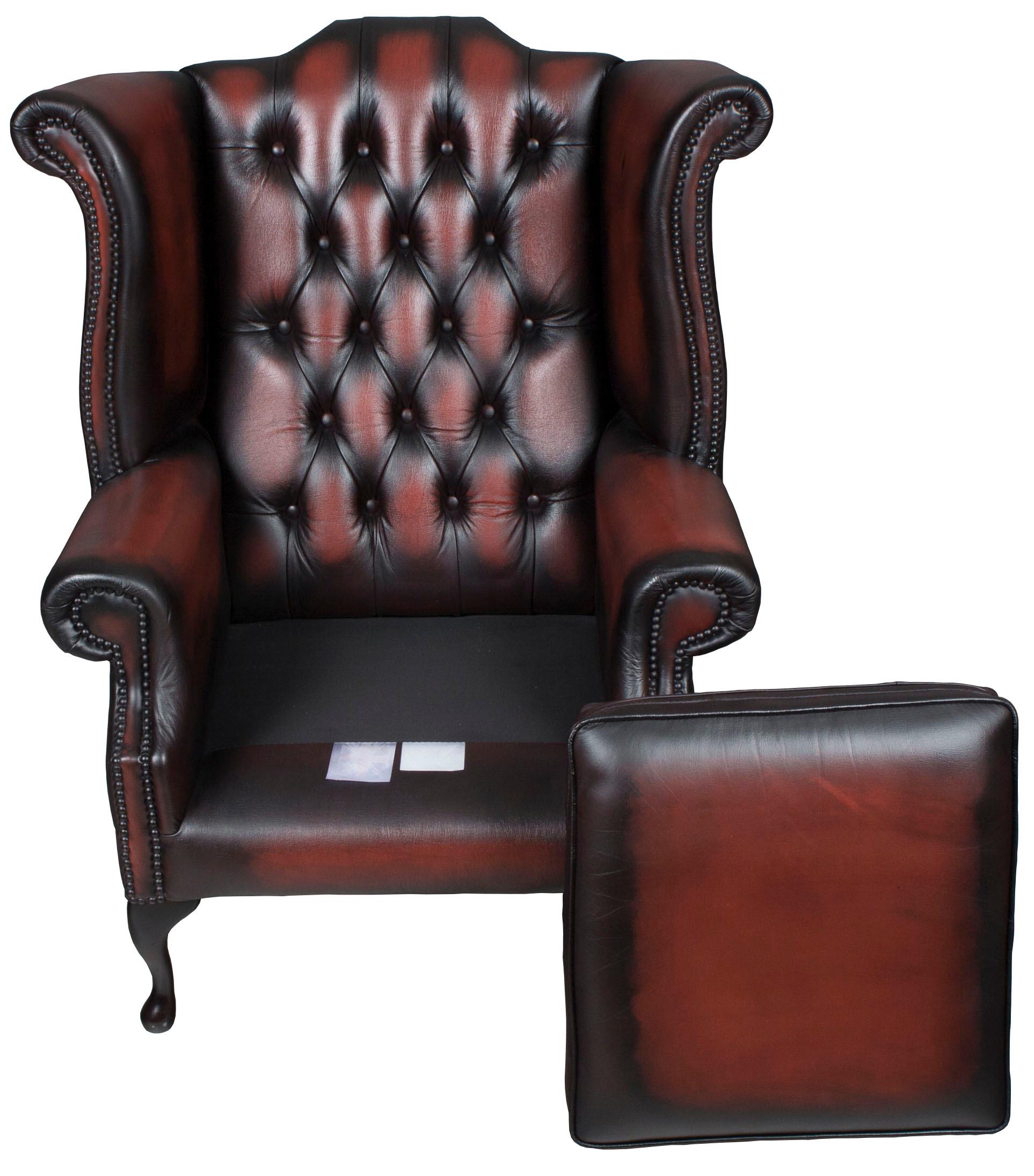 This exquisite red leather wing back armchair was crafted in England around 1980. Designed in a traditional Queen Anne style, this beautiful wing back chair features rich red leather, brass brads, and mahogany pad feet. The leather is quite stunning