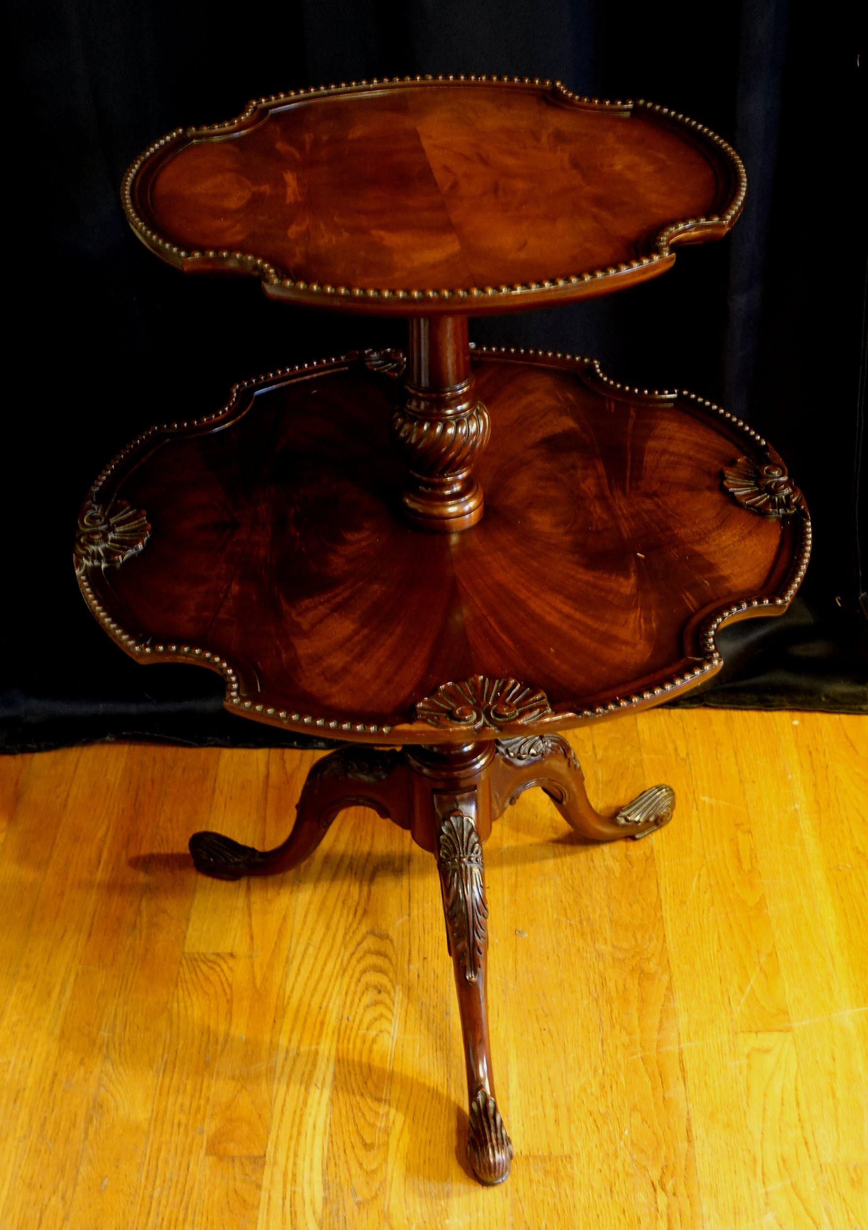 English Queen Anne-style (mid-20th century) mahogany two-tier dumbwaiter table on a turned pedestal base supported by three cabriole legs with carved acanthus leaf feet. Measures: height: 33.5
