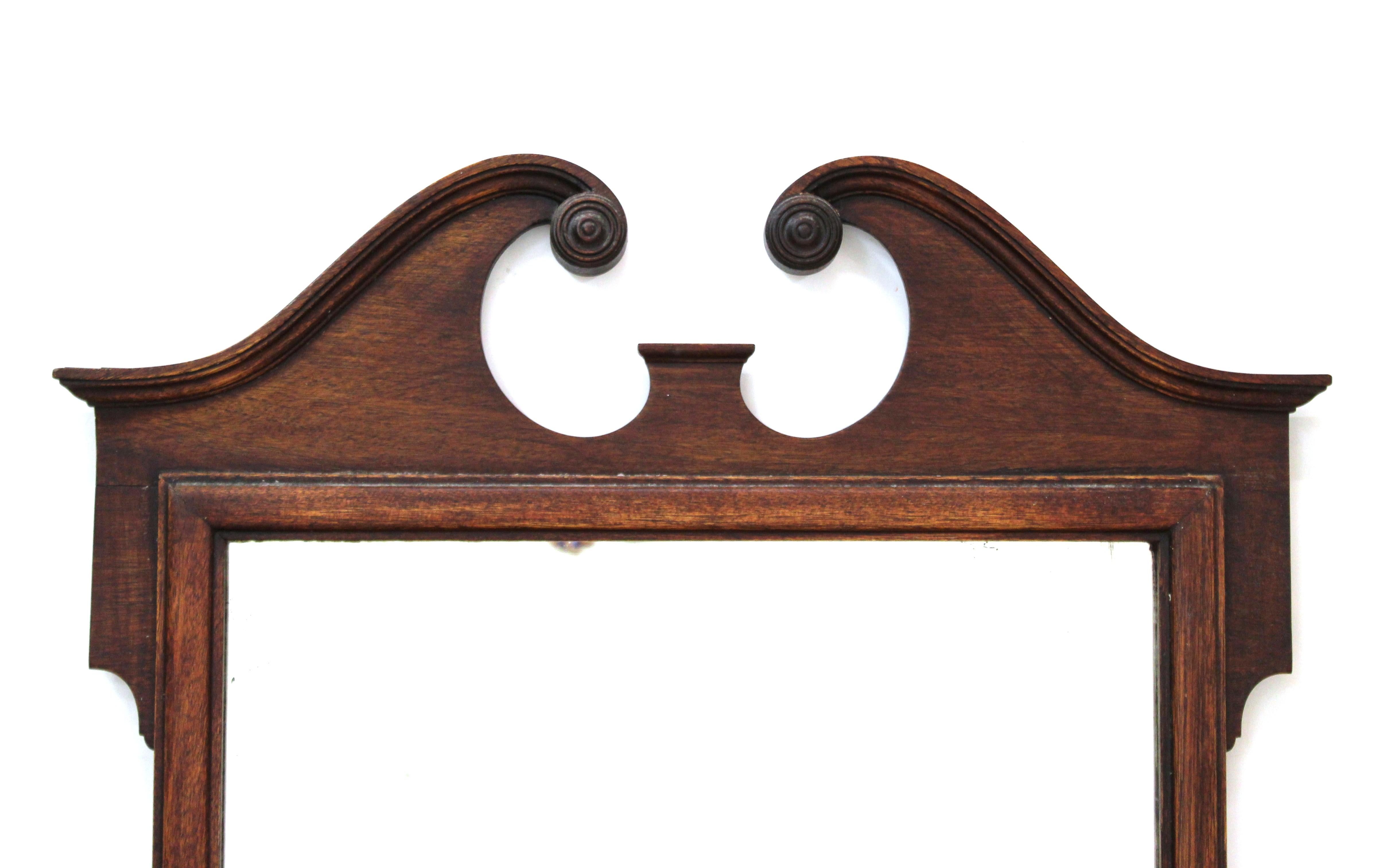 Queen Anne style wall mirror with carved wood frame and broken pediment. Made in the 19th century, the piece is in great antique condition with age-appropriate wear and use.