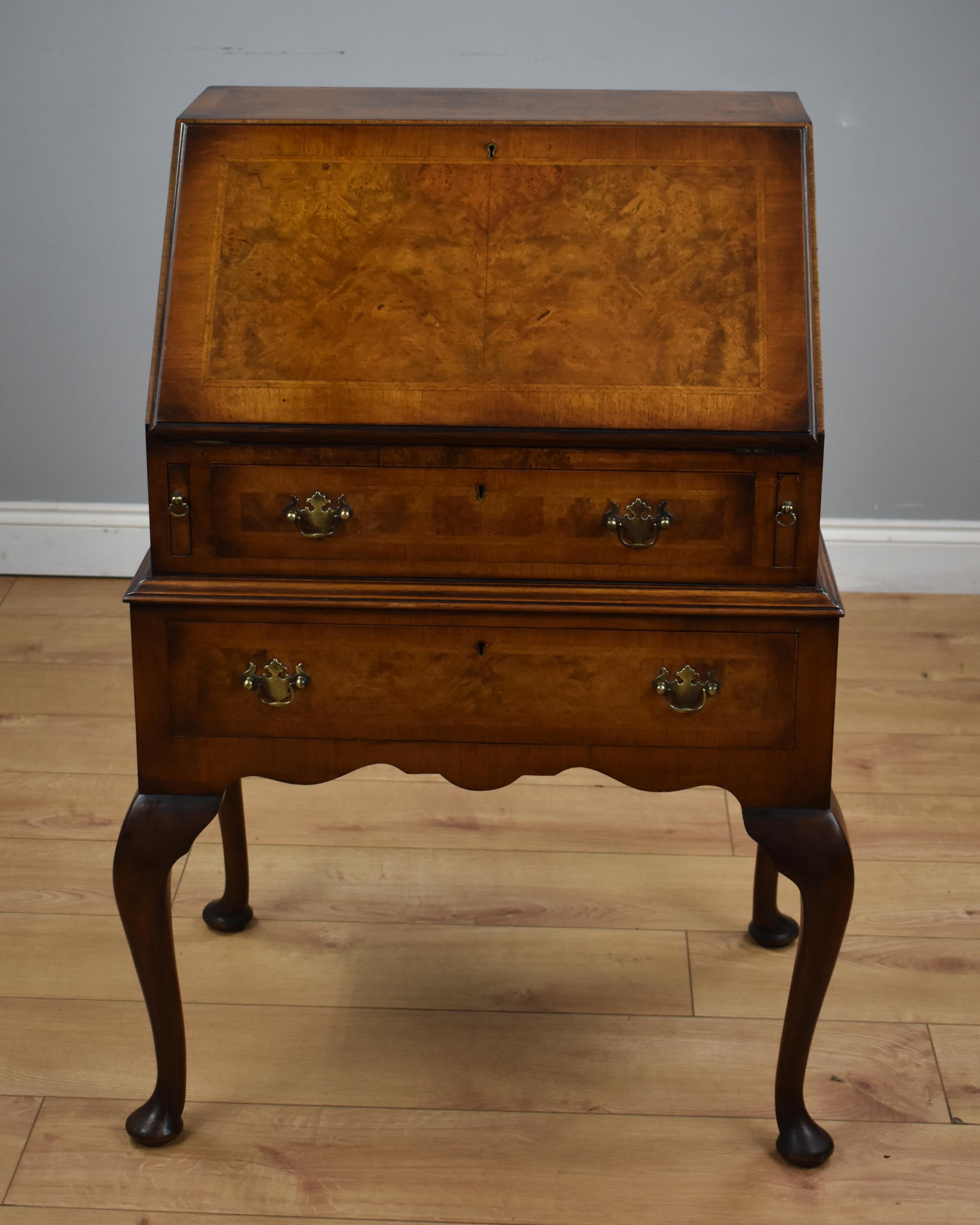 Queen Anne style walnut Bureau in good condition. The fall front conceals a shaped interior with two small drawers, pigeon holes and centre cupboard. Below the top it has two long drawers with brass handles and stands on cabriol legs.