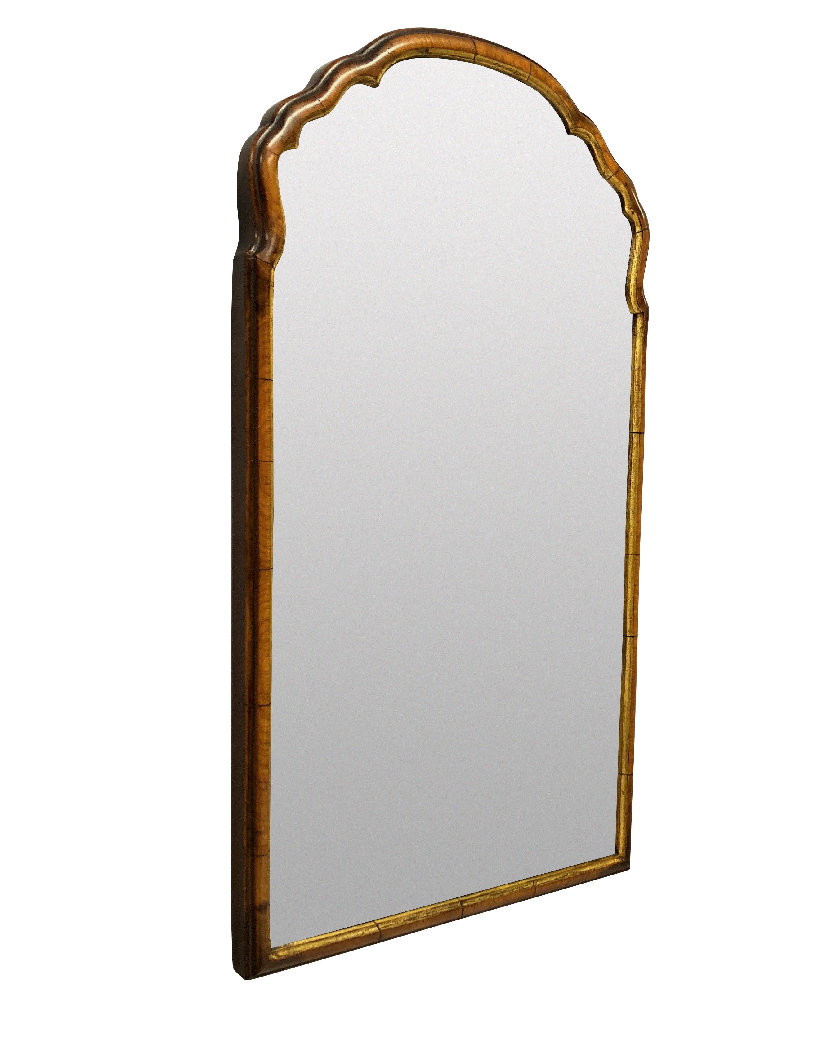 A charming little Queen Anne style mirror in walnut, with a parcel gilt slip.