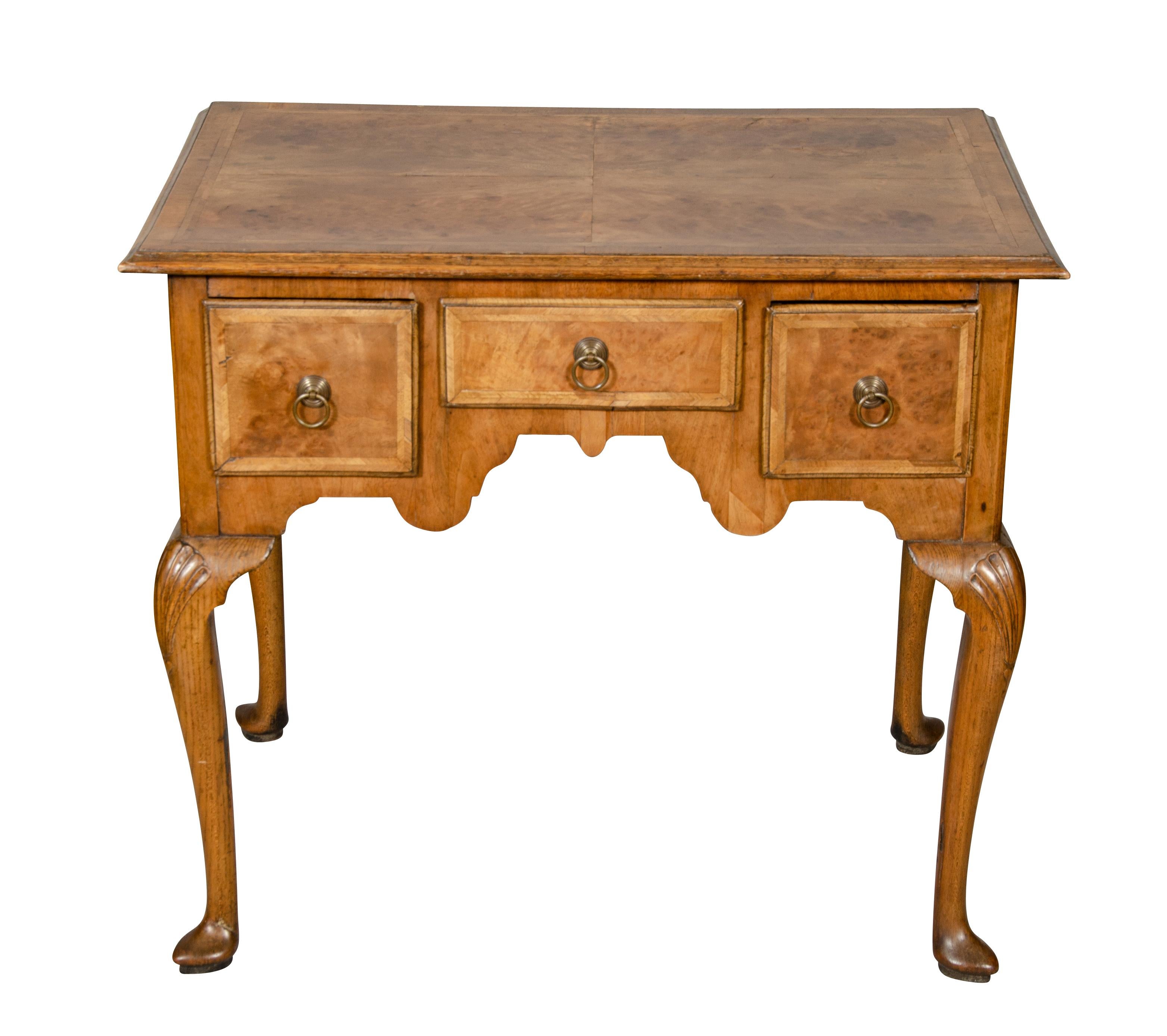 Encimera rectangular chapada en cuarto sobre un cajón central flanqueado por un par de cajones elevados sobre patas cabriolé, pies almohadillados.