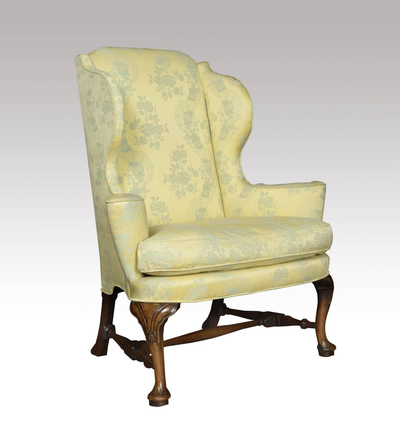 Queen Anne style wing armchair having walnut front carved cabriole legs, with swept legs to the rear united by stretcher. The wing armchair upholstered in damask upholstery having removable cushion.

Dimensions: 

Height 44 inches height to seat