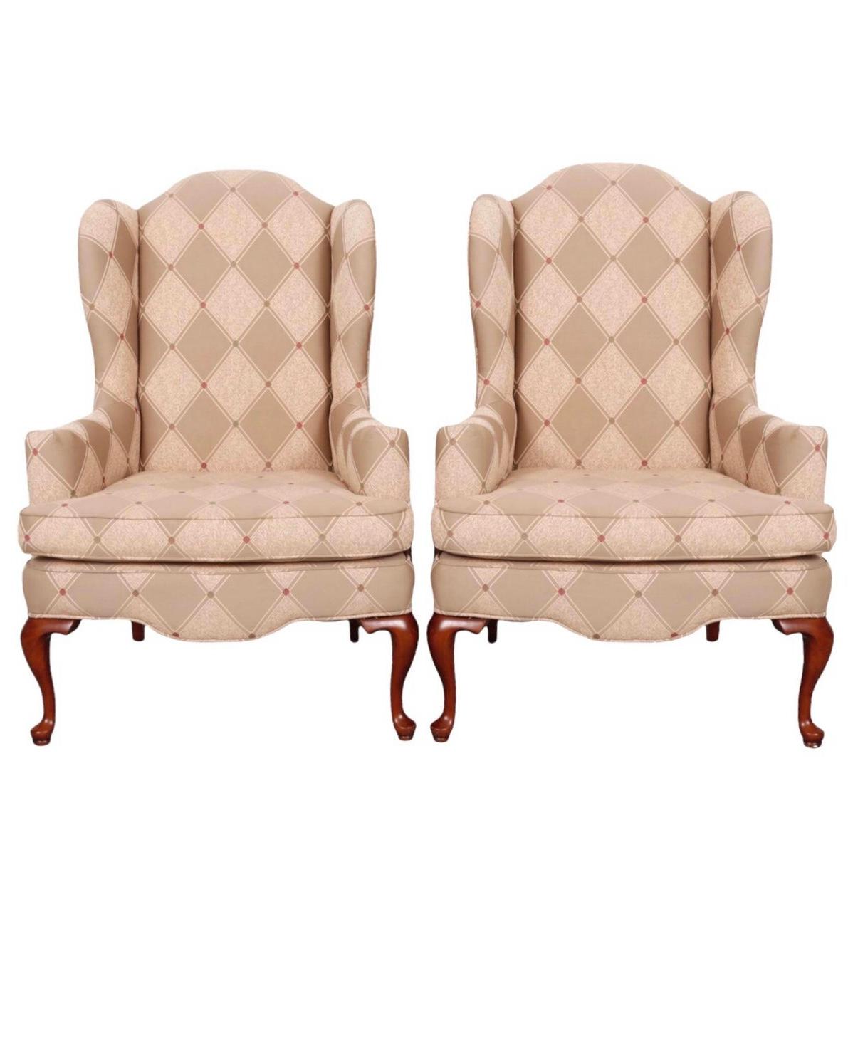 A pair of Queen Anne style wingback chairs. Elegantly curved wings flow into outward rolled, button topped arms, which frame a trapezoid shaped seat. Upholstered throughout in a diamond embossed taupe brocade detailed with brown, sage and wine