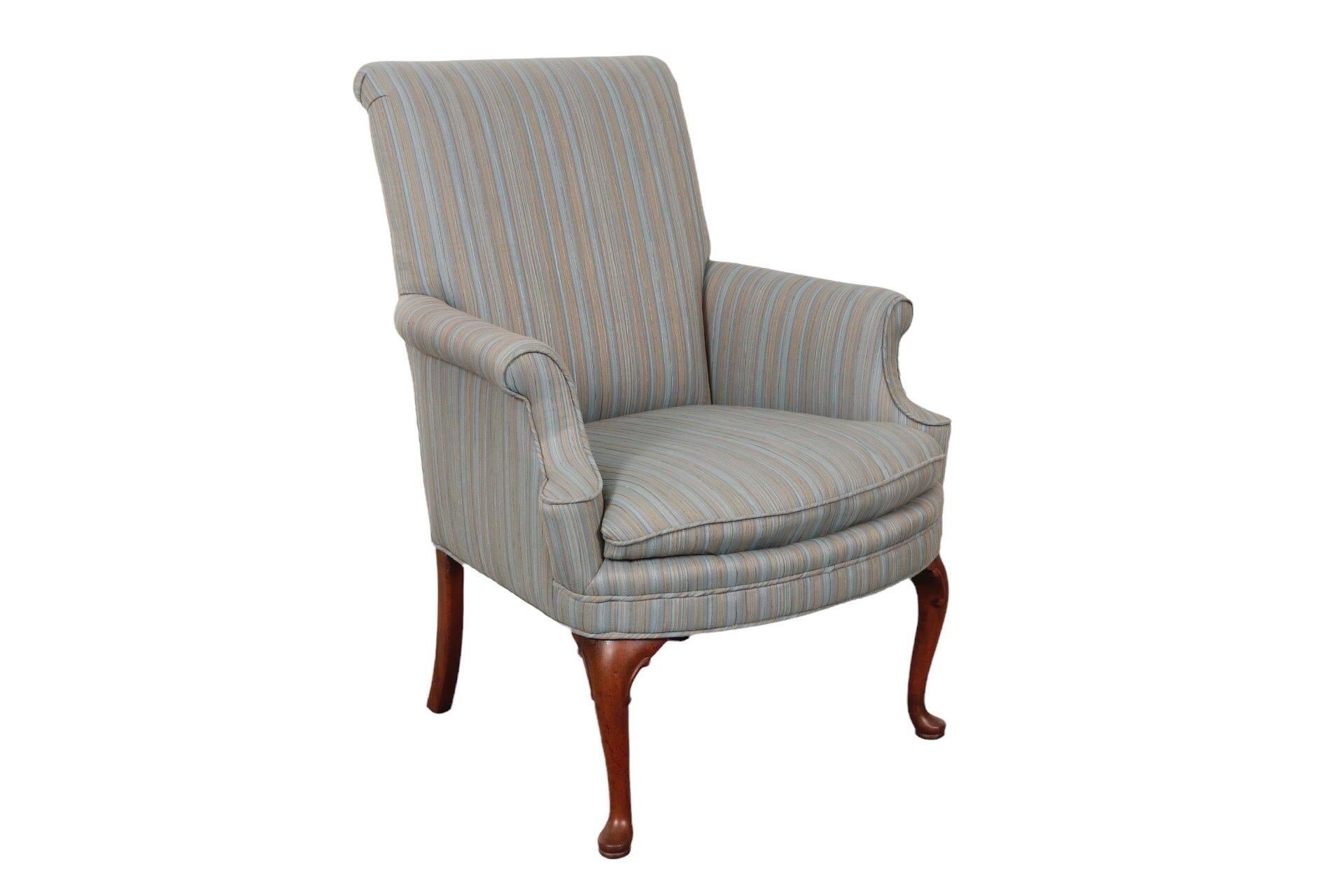 A Queen Anne style upholstered armchair. The horseshoe shaped seat is framed with outward rolled arms and a gently reclining back, topped with a flat crest rail. Upholstered in a vintage blue strie basket weave fabric threaded with brown and yellow