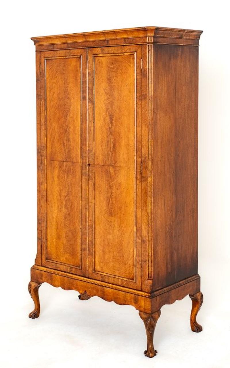 2 Door walnut Queen Anne style wardrobe.
Circa 1920
This piece stands upon cabriole legs with a carved shell to the knee and shaped feet. The shaped frieze having a carved central shell.
The doors being of a paneled form with cross grain moldings.