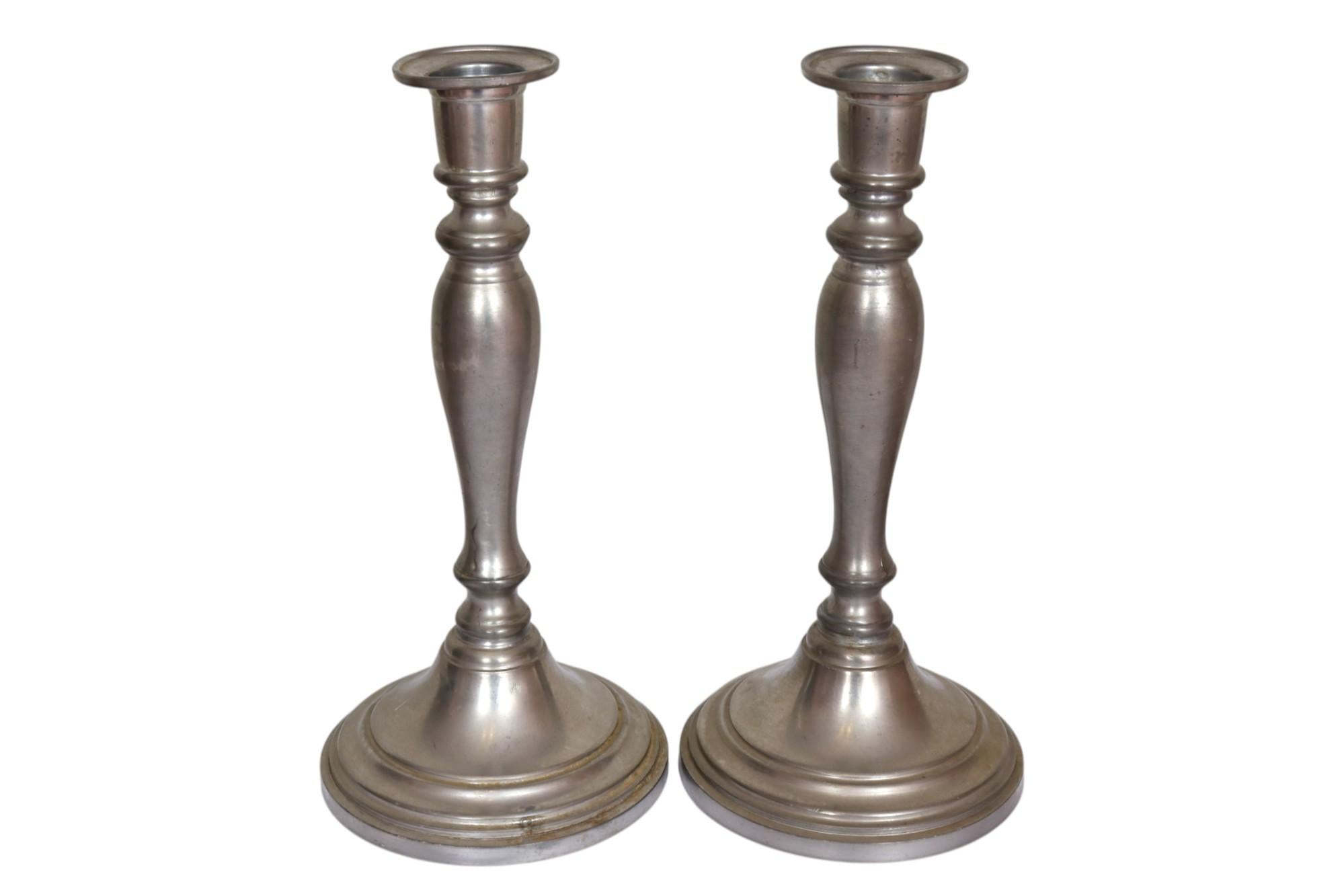 Ein Paar traditioneller Kerzenständer von Queen Art Pewter, Ltd aus Brooklyn, NY. Die handgefertigten Zinnsäulen mit gedrehten Balustern sind mit einfachen Kapitellen und abgeschrägten Basen versehen. Darunter steht 