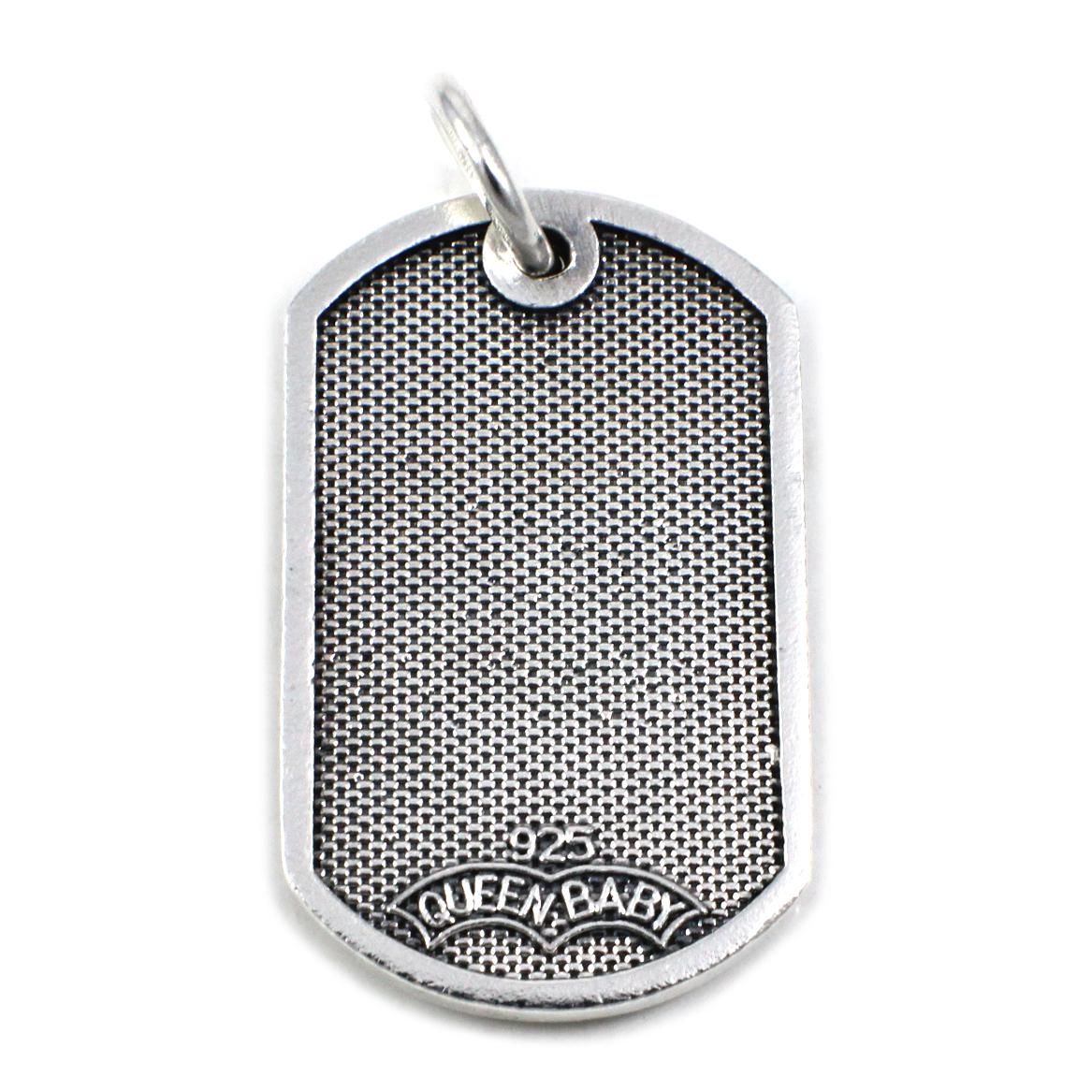 This pendant is made in sterling silver by designer Queen Baby. The dog tag is set with a cross in the front, and it is signed 