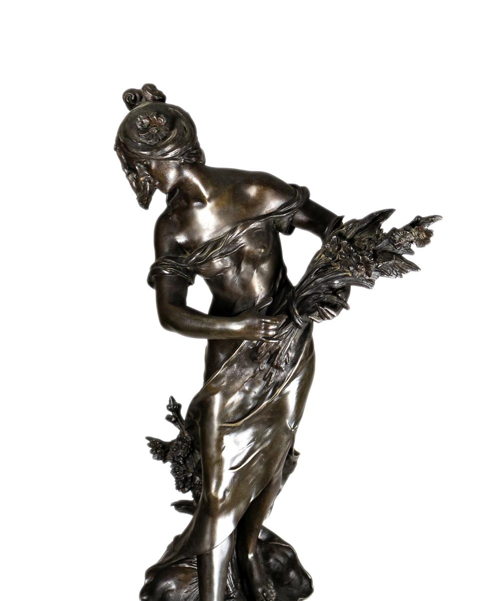 Belle-Époque-Statue und -Säule aus Zinn aus dem späten 19. Jahrhundert: Königin der Felder / Reine Des Pres, eine junge Frau in wallendem Kleid mit einem Weizengesteck in der Hand.
Signiert 