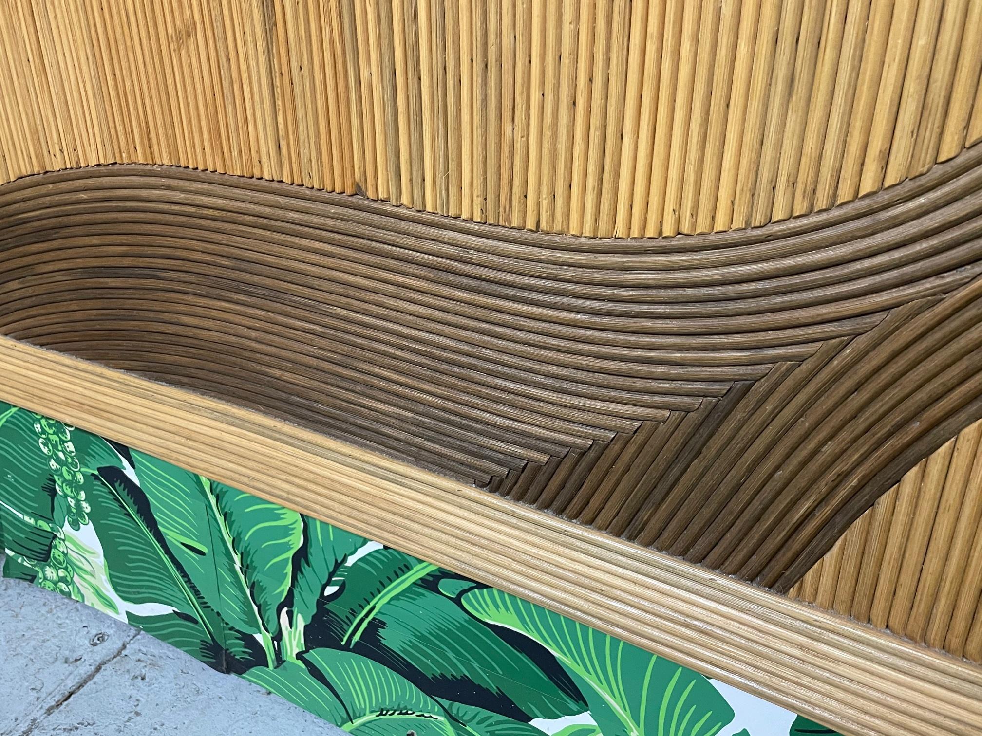 Queen size rattan bed headboard features full veneer of pencil reed rattan in a decorative pattern. In the style of Betty Cobonpue. Very good condition with only minor imperfections consistent with age.