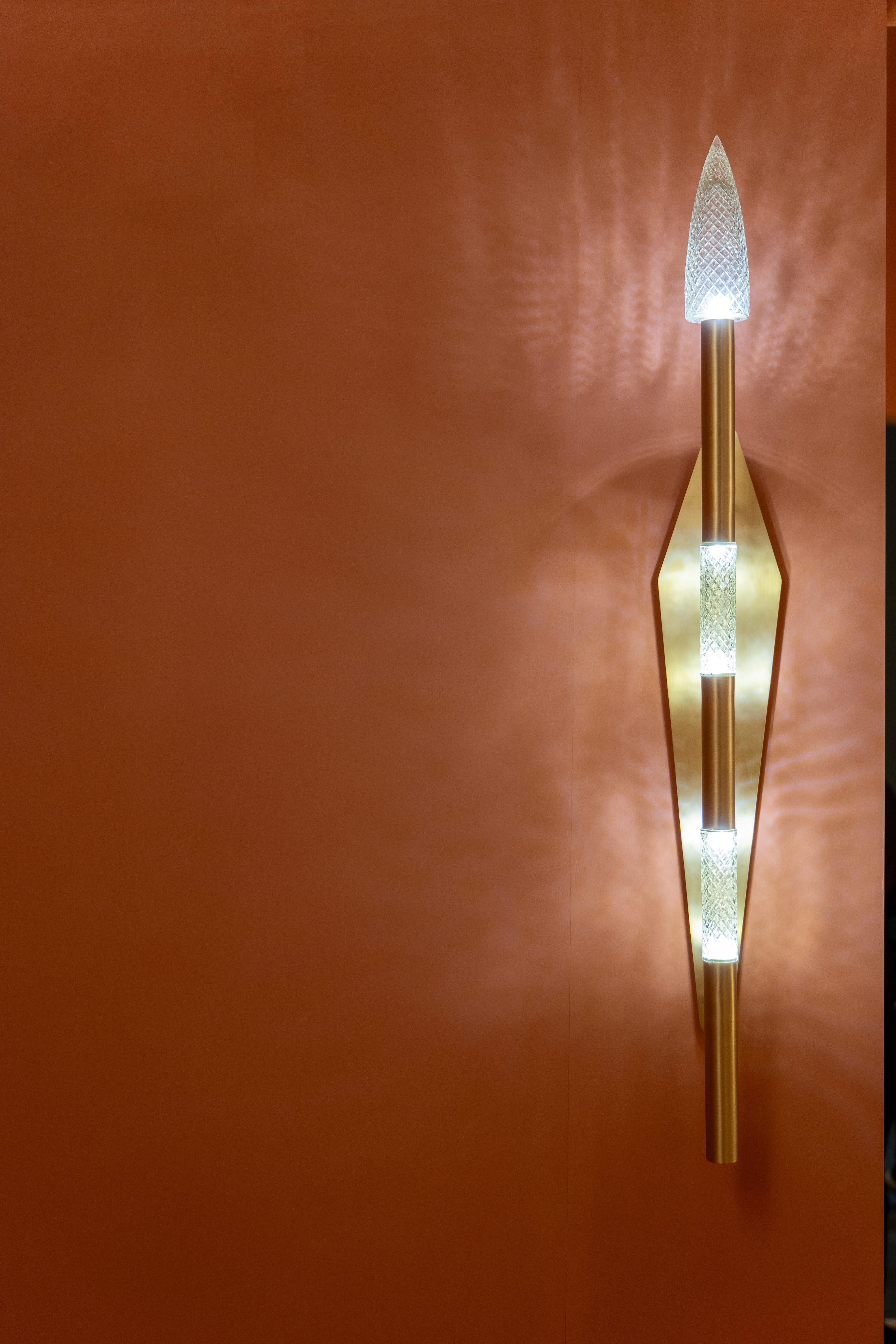 Elevate your interiors with this stunning contemporary wall lamp, a perfect fusion of luxury and innovation. Crafted with a sleek matte gold finish, the design features a vertical rod accented by precision-cut crystal-like diffusers that create a