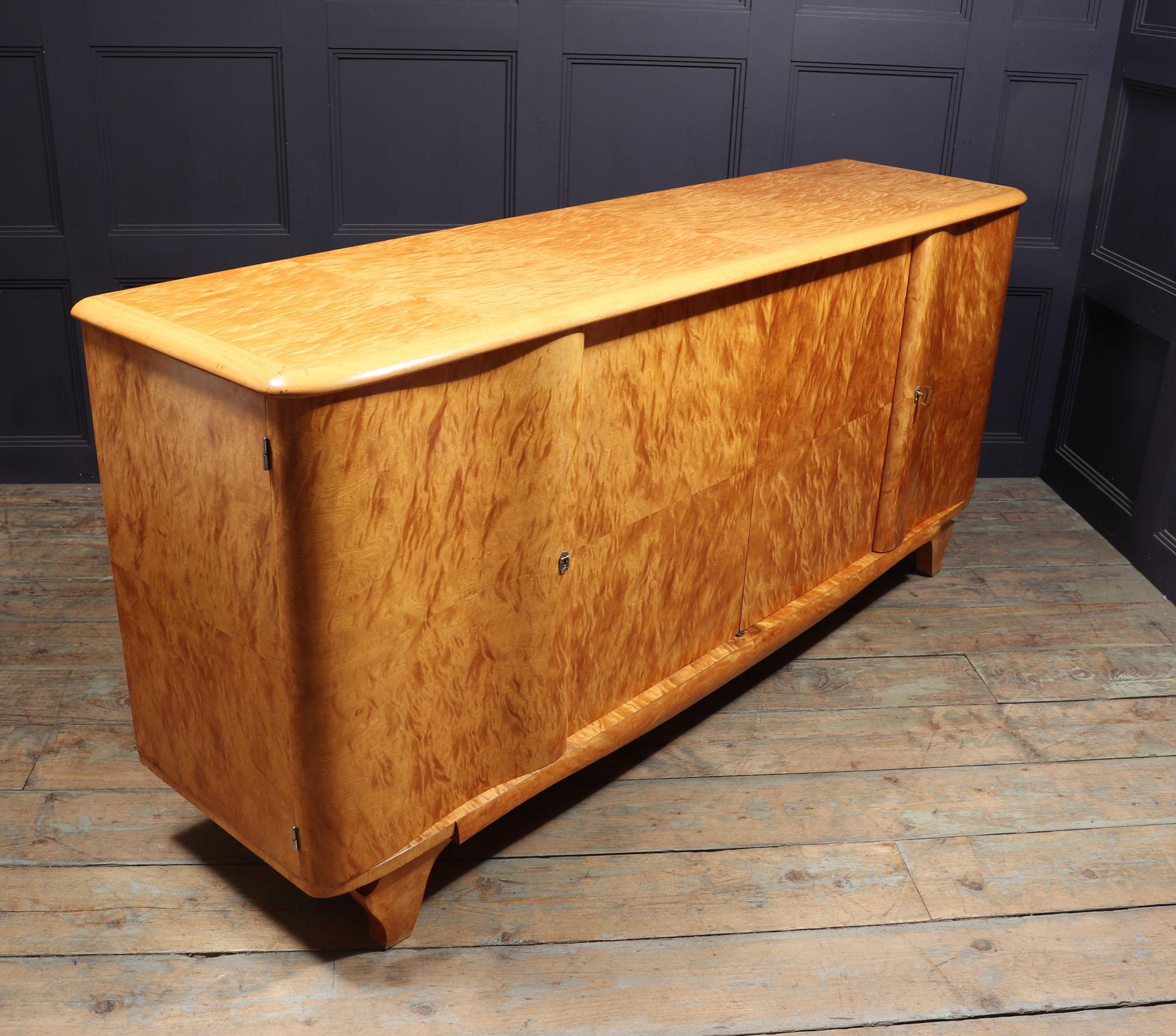 A very good quality four door sideboard in quilted maple, with shaped outer doors that close over the inner doors, locks are working with original key, shelves behind and one internal drawer, the sideboard has been fully polished and in very good