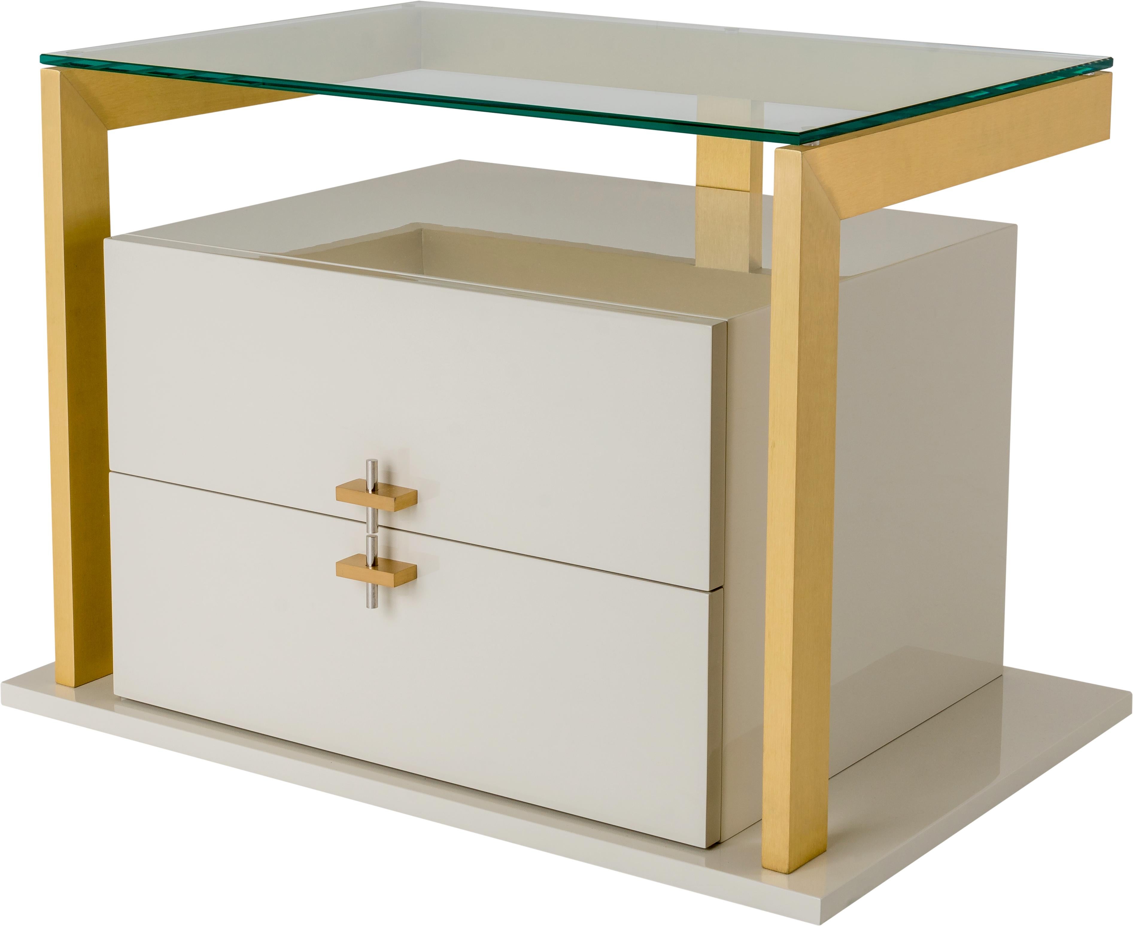 QUIMERA is a modern and elegant bedside table characterized by a metal structure, brushed brass or polished stainless steel, with two lacquered wooden drawers, surmounted by a tempered glass top.‎ The design of Quimera is completed by brass handles