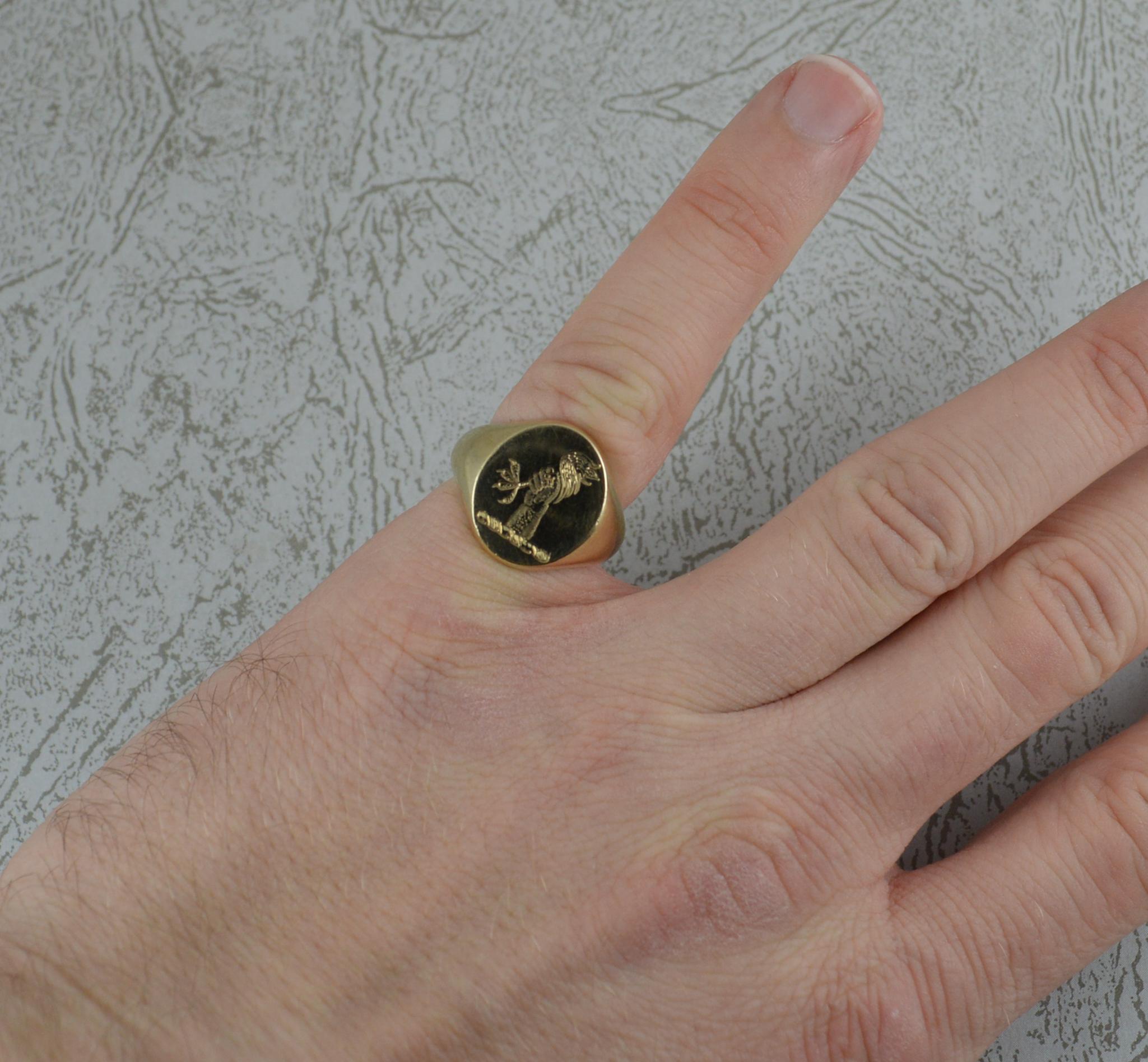 A superb chunky and heavy 9 carat gold signet ring.
9 carat yellow gold example with oval front.
13mm x 15mm head. Engraved with an arm reaching out of the ground holding a chicken leg.

CONDITION ; Very good. Clean solid shank. Light wear to band.