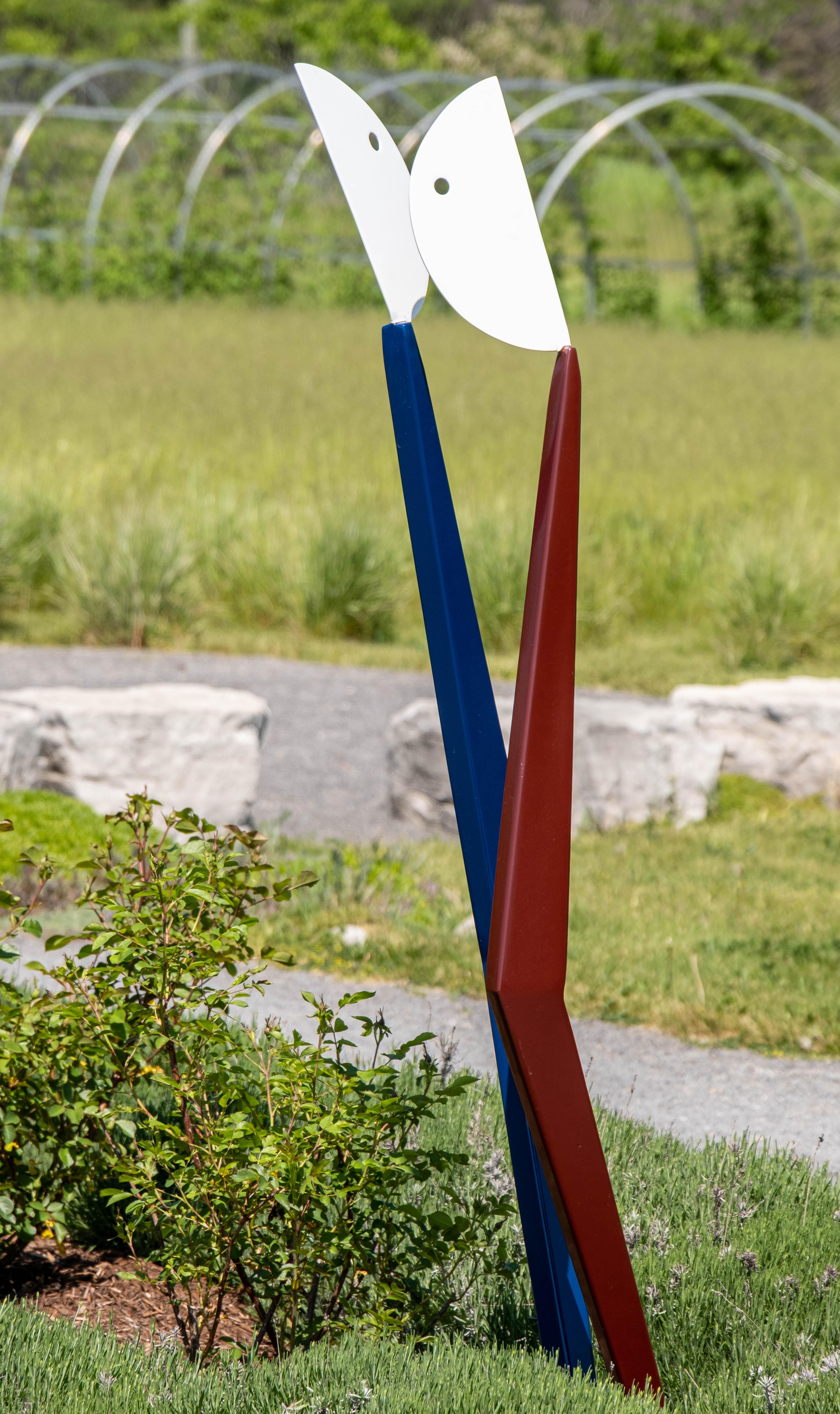 In this engaging abstract sculpture by Robert Clarke-Ellis two figures appear to dance together. White painted half-moon shapes top blue and red stick-like pieces that intersect as if embracing one another. The Toronto artist creates expressive