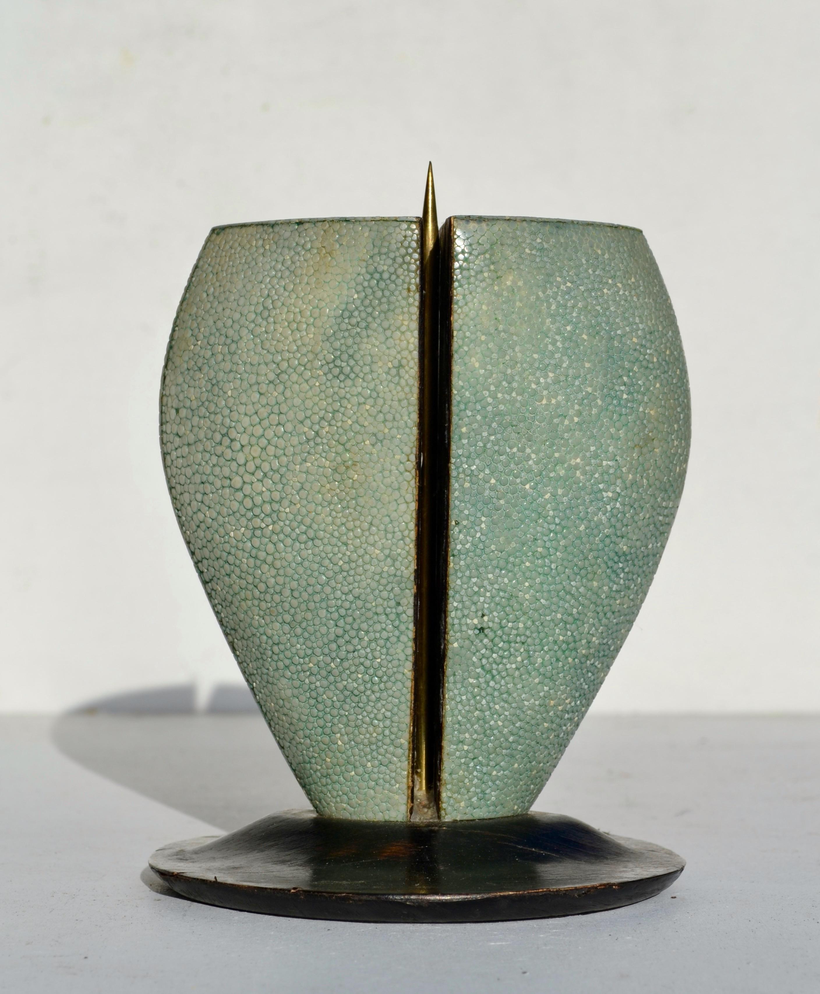 Un raffinato e scultoreo portacandele di R & Y Augousti, Parigi/Londra, noti per l'uso magistrale dello zigrino e di silhouette organiche e sensuali.
Il pezzo è caratterizzato da una forma volumetrica simile a un baccello rivestito di verde mare,