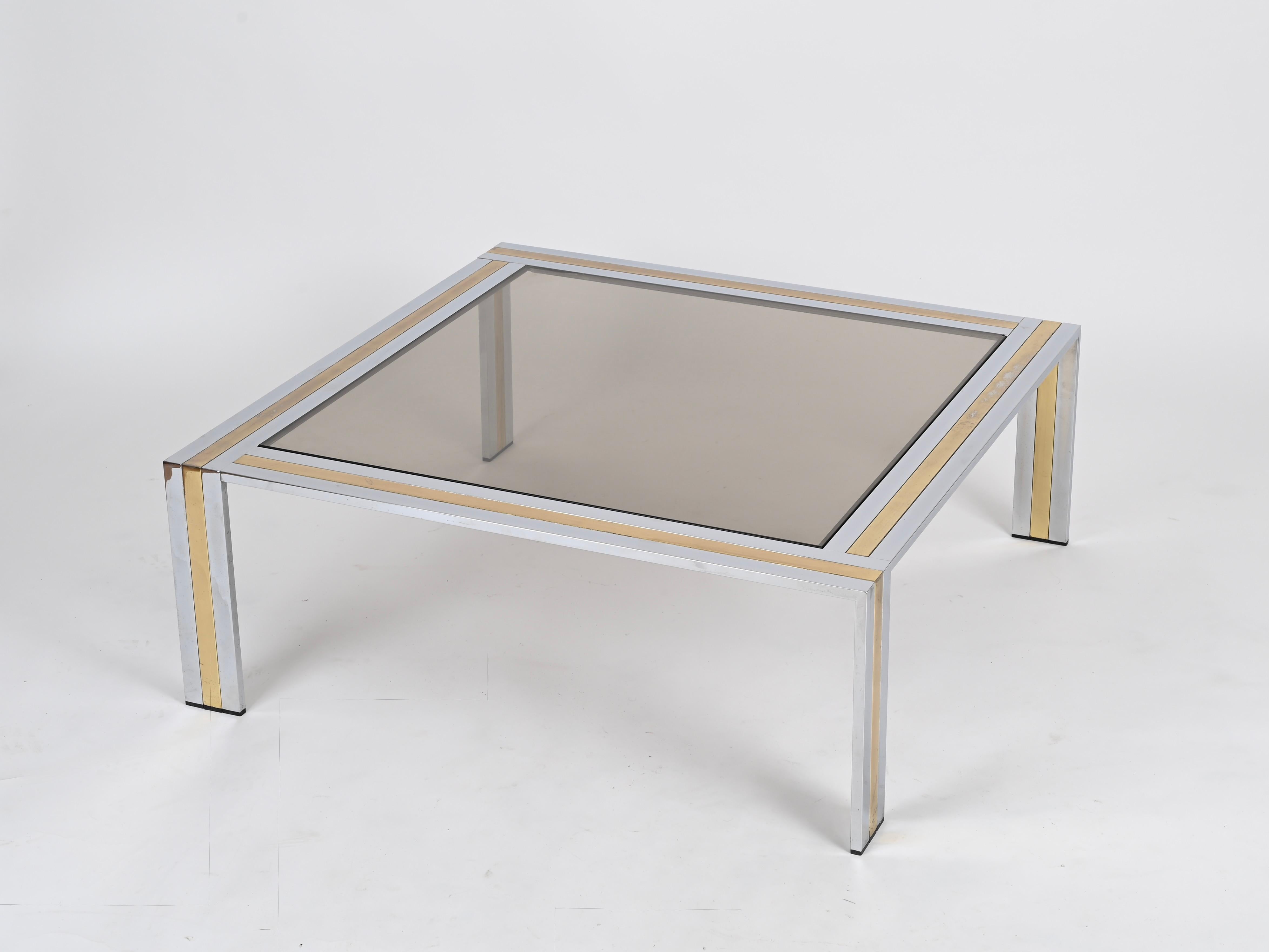 Magnifique table basse carrée en chrome et laiton avec un plateau en verre fumé. Cette table basse élégante et incroyablement stylée a été conçue par Renato Zevi et produite en Italie dans les années 1970.

Cette pièce étonnante présente une