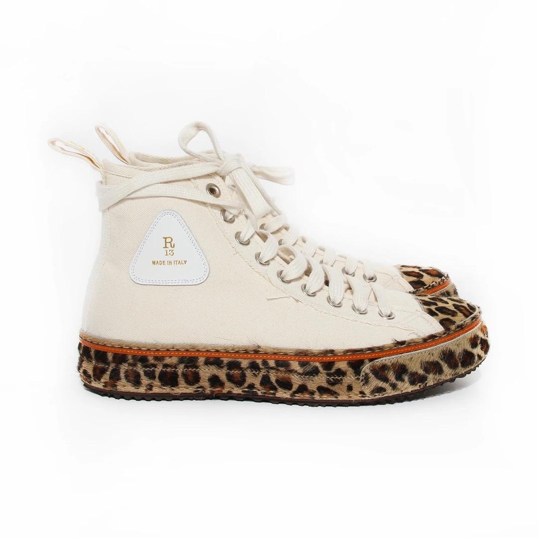 R13 Canvas Sneaker 
Made in Italy 
High top style sneaker 
Beige canvas 
Triangular leather detail with R13 stamped in gold on outside of shoes
Beige laces 
Leopard print pony hair along sole 
Orange leather detail at sole 
Rounded toe with leopard