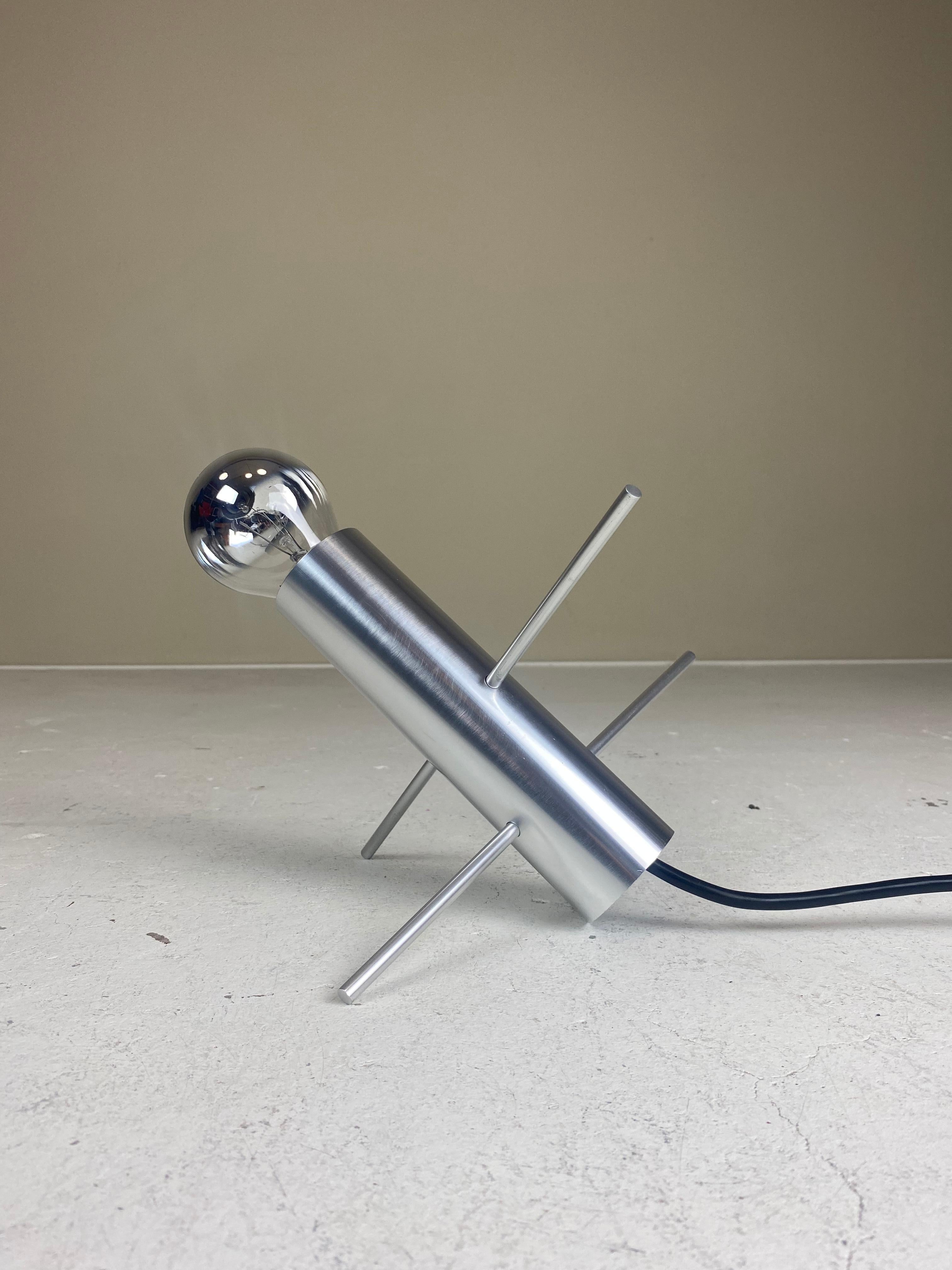 This stunning R-60 ‘Cricket’ table lamp was designed in 1962 by Otto Wasch for Raak Amsterdam. It consists of a polished metal cilinder with two pins in it, a touch of minimalist genius. By changing the postion of the pins, the lamp can be placed in