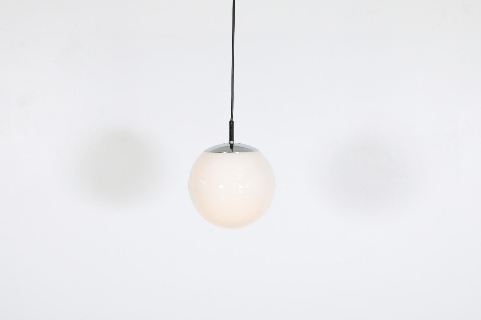 Attractive, Mid-Century, RAAK (attr) vintage opaline glass globe pendants with chrome hardware. Simple, classic but fantastic Dutch design. Globes are semi-transparent when looking up at them. In good original condition with visible wear consistent