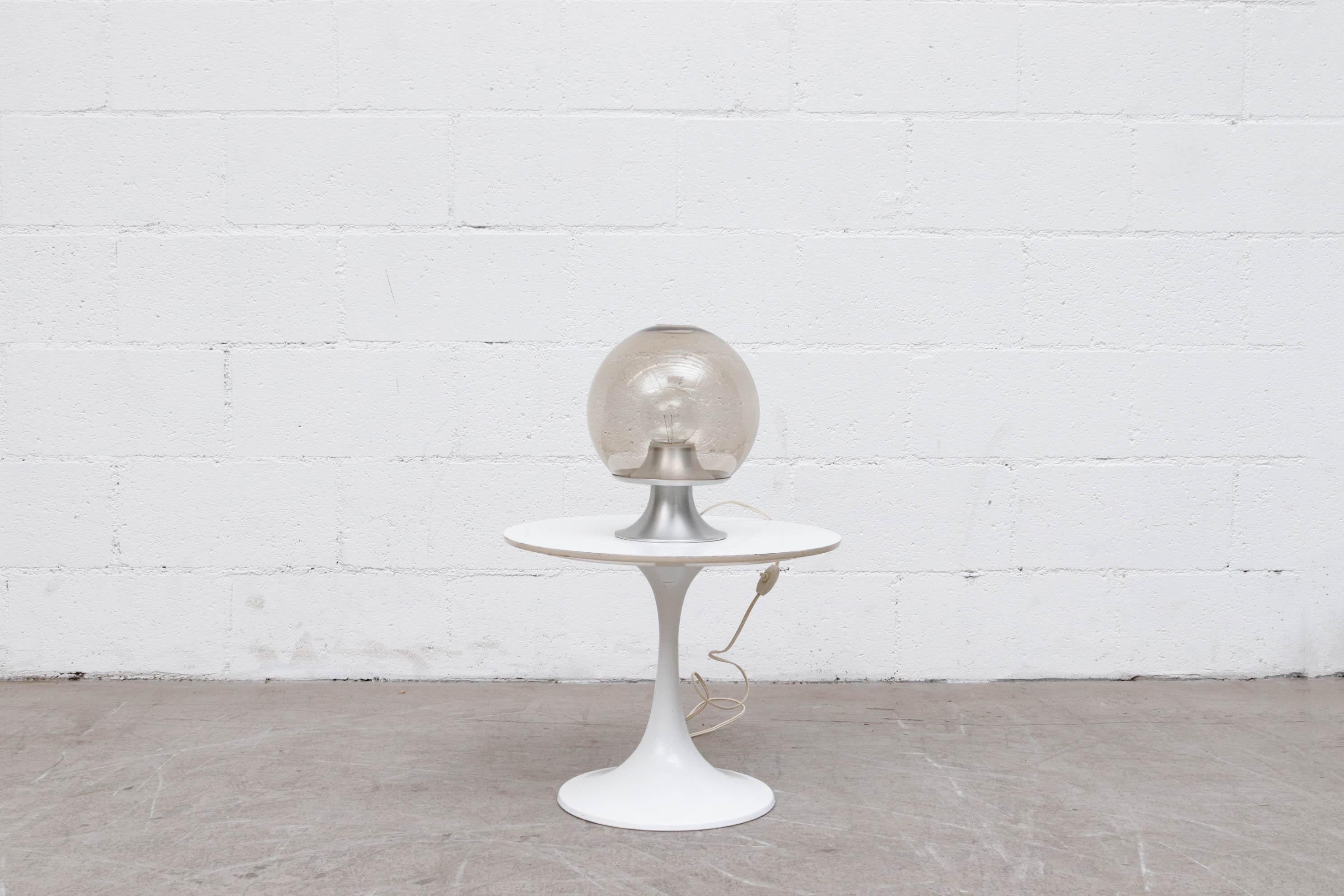RAAK blown glass globe table lamp. Smoke globe sits on a spun aluminum pedestal base. Aluminum shown visible wear consistent with its use and age. Globe is 8.25