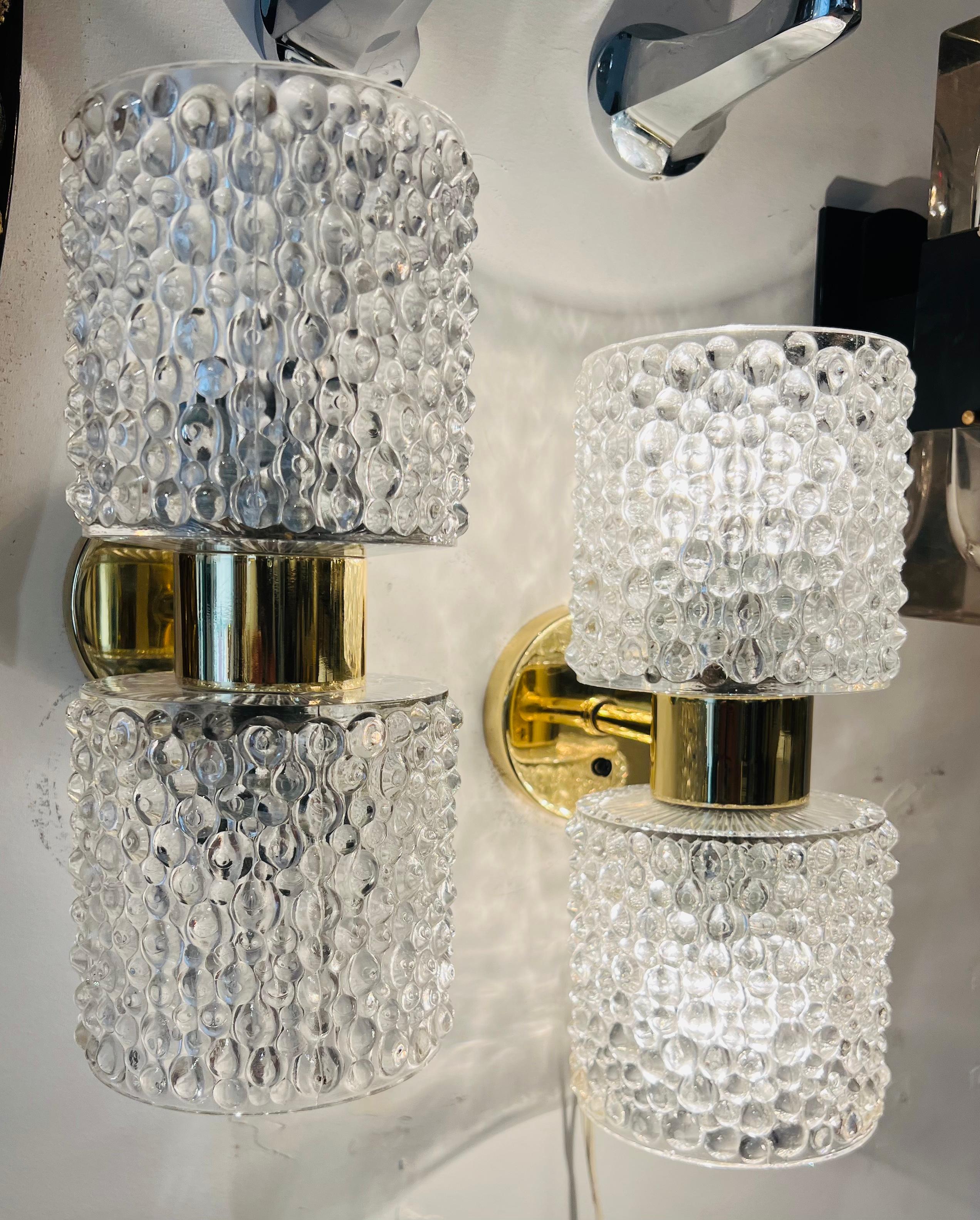 A stunning pair of golden polished brass sconces with heavy bubble crystal glass shades by the famed Dutch lighting company, Raak. Newly rewired. Two candelabra sockets per wall lamp.