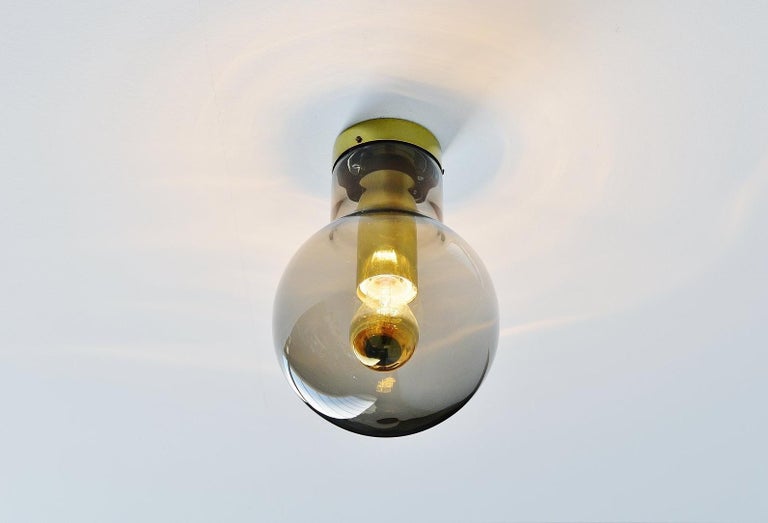 Very nice flush mount lamp designed and made by Raak Amsterdam, The Netherlands 1965. This lamp is called Maxi Globe and this is the smallest version available. The lamp has brown-grey fume glass and a brass fixture. It can be used as ceiling lamp