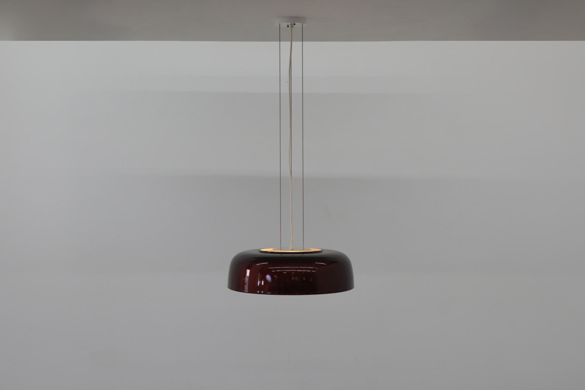 Lámpara suspendida de mediados de siglo con pantalla abovedada de cristal esmaltado metalizado burdeos, de RAAK. En su estado original, con los herrajes originales de la suspensión de cadena de talón y algunos arañazos visibles en la pantalla, así