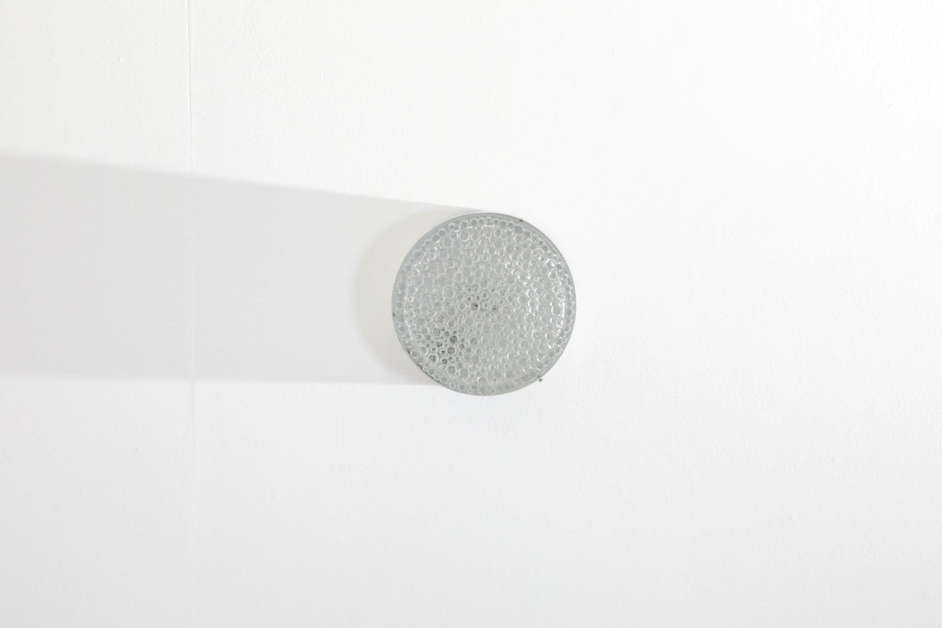 RAAK, vintage pill shaped ceiling or wall sconce with heavy pressed glass shade and a spun aluminum casing. In original condition with visible wear consistent with its age and use. Condition may vary. Two available, sold individually.