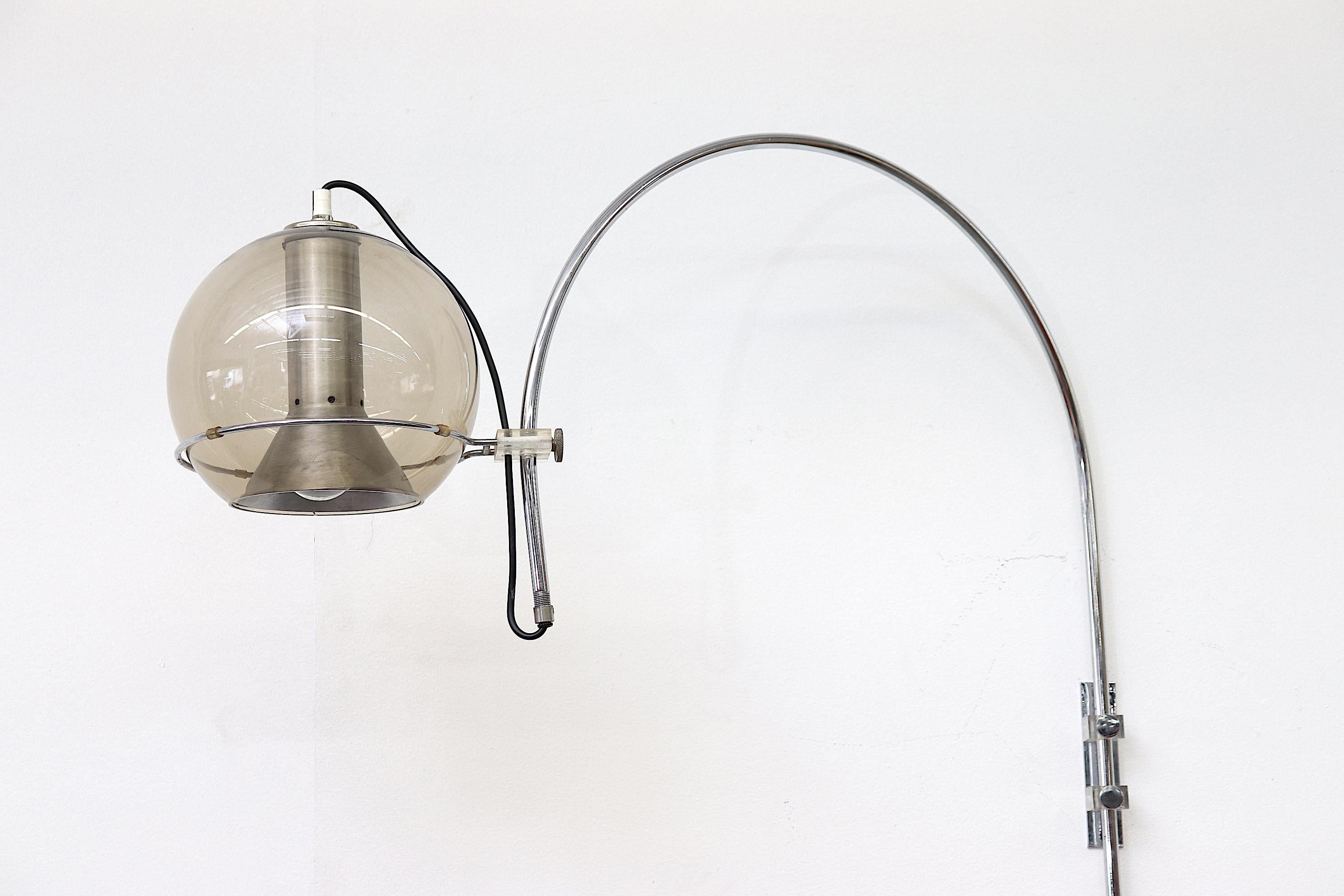 Raak globe wall mount arc light by Frank Ligtelijn with smoked glass globe shade and signature aluminum funnel insert. Height-adjustable swing arm movement. Chrome with Lucite accents. In original condition.