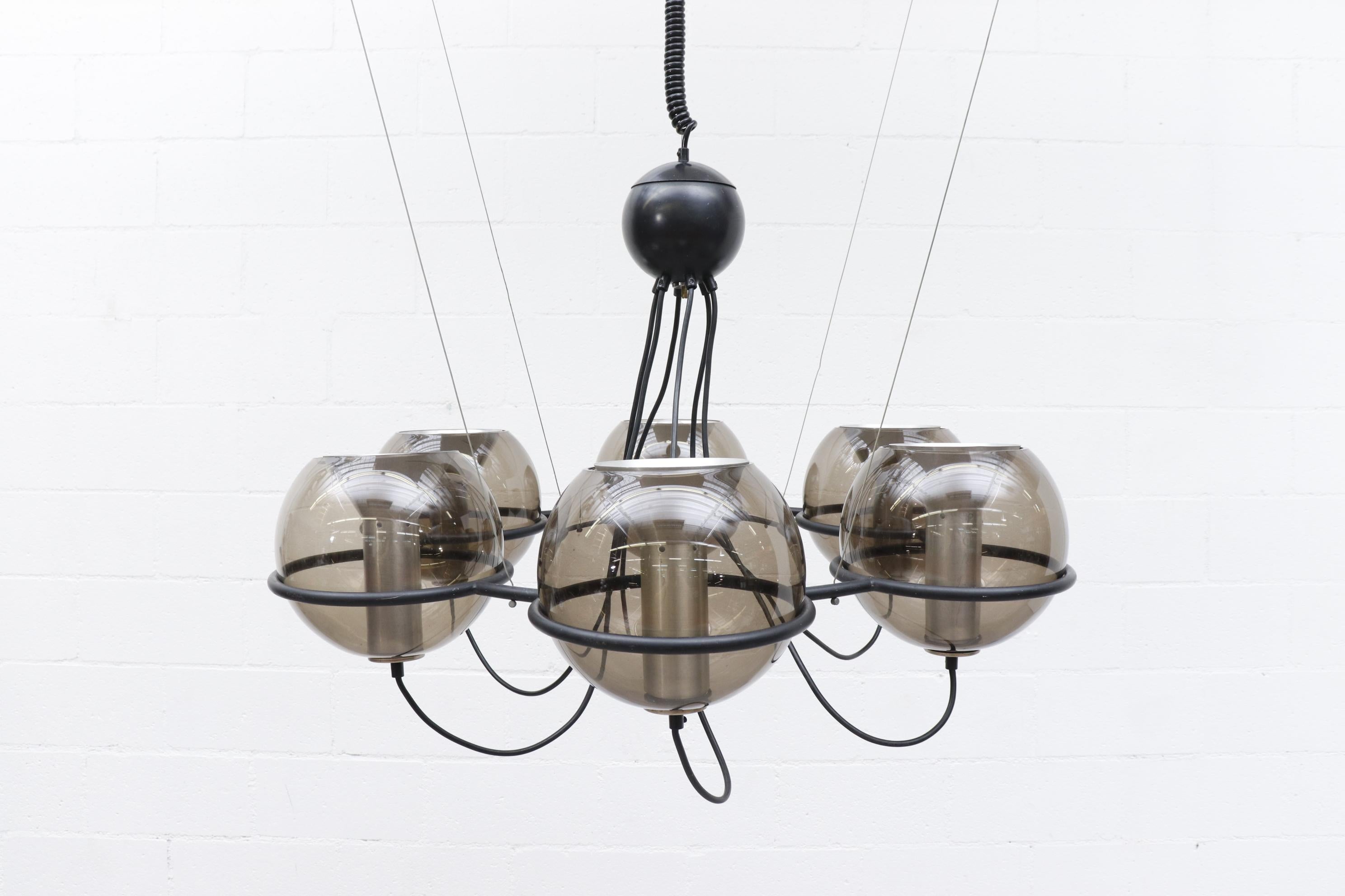 Midcentury RAAK  'Girandole' chandelier with six smoked blown glass globes on a black metal frame. Innovative at the time for showing exposed wiring and hardware. Shown in 2 possible configurations; 1) with spots pointing upward, and 2) as shown in